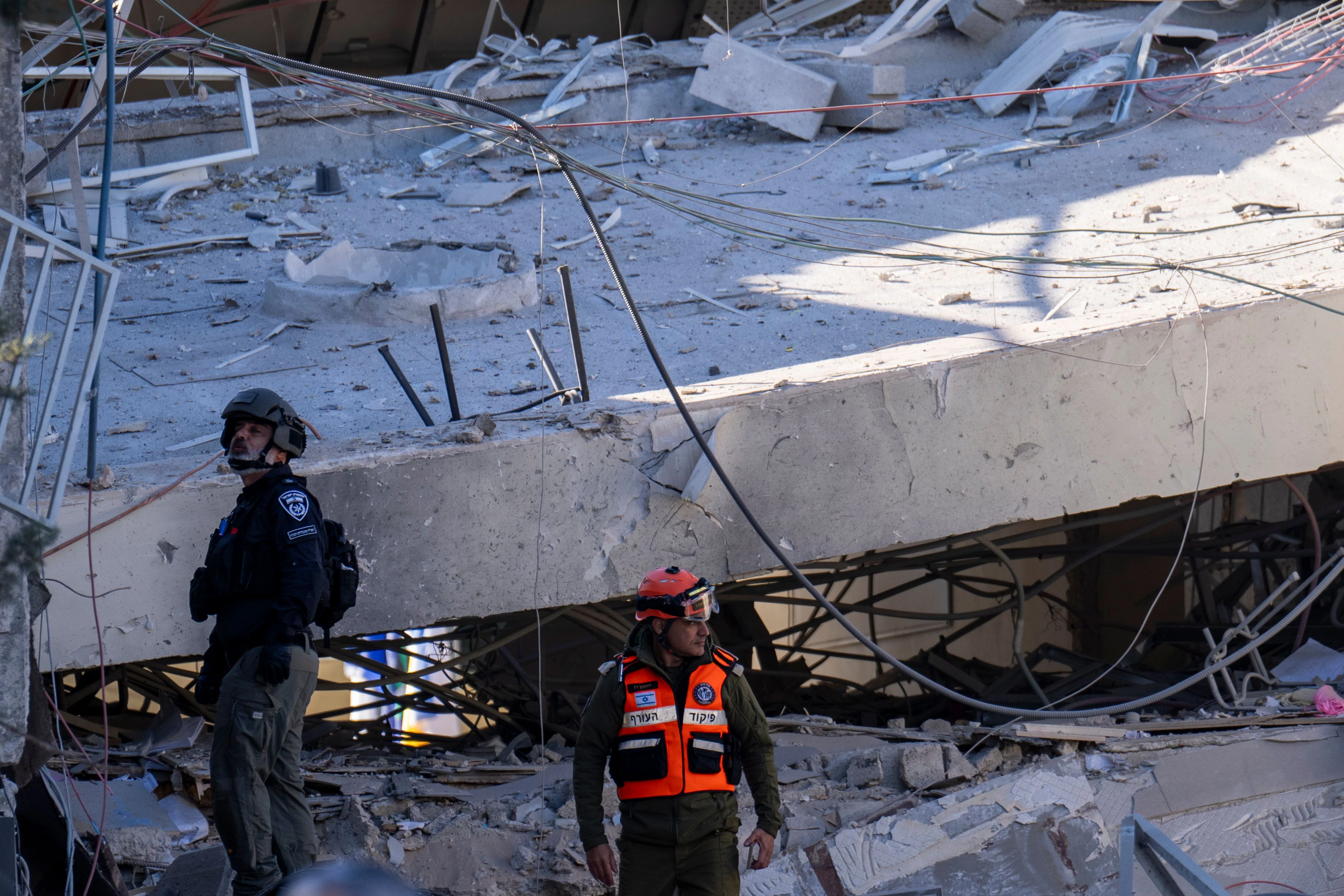 Israel, Ramat Gan: Ein Offizier der militärischen Einheit des Heimatfrontkommandos und ein Polizist begutachten den Schaden, nachdem ein großes Stück Schrapnell einer Huthi-Rakete ein Schulgebäude in Ramat Gan, einem Vorort von Tel Aviv, zum Einsturz gebracht hat. 