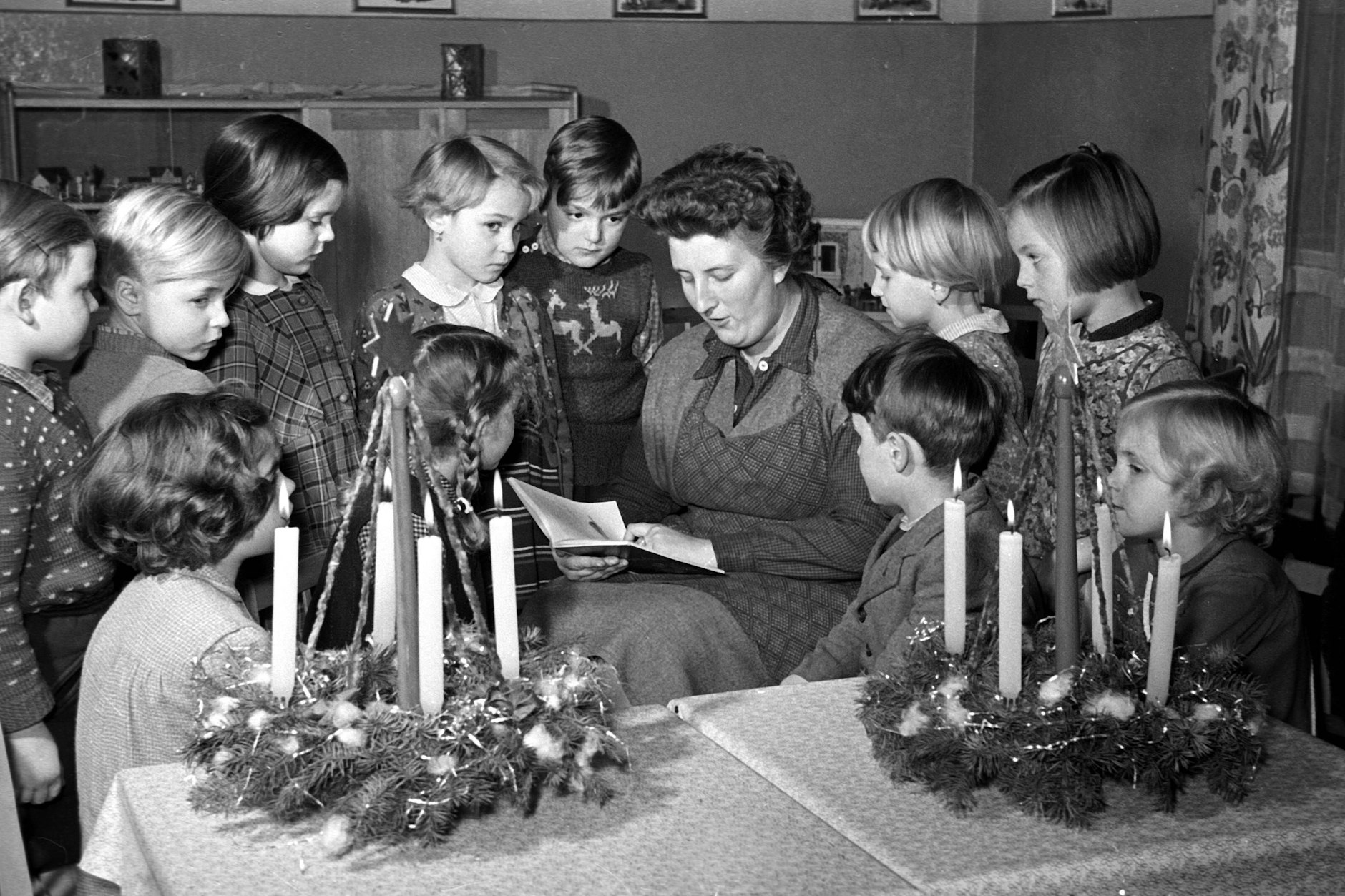 Wir schreiben das Jahr 1956: Eine Erzieherin liest Kindern aus einem Weihnachtsbuch vor.