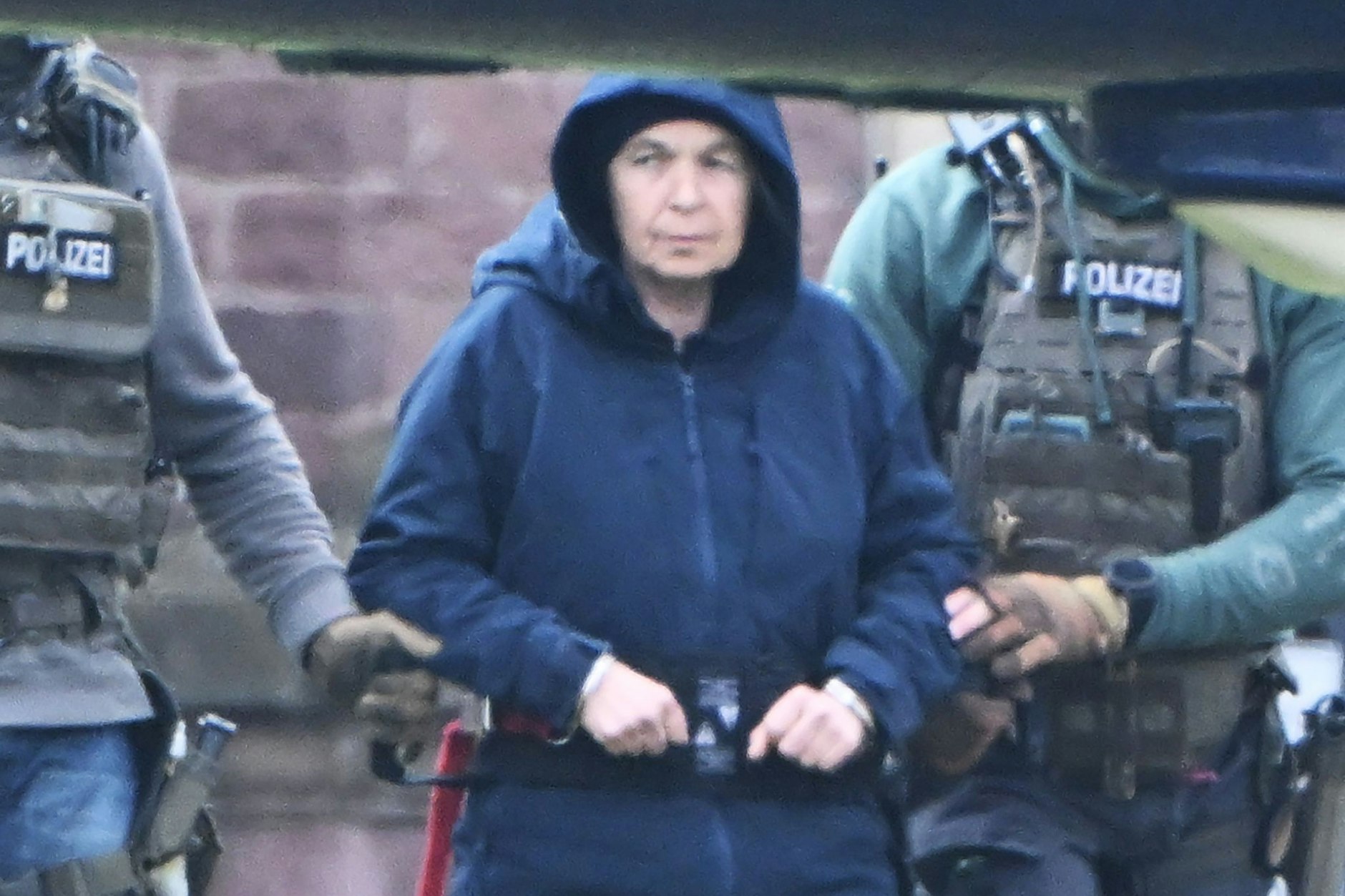 Im Innenhof eines Behördenzentrums wird die frühere RAF-Terroristin Daniela Klette zu einem Hubschrauber geführt.