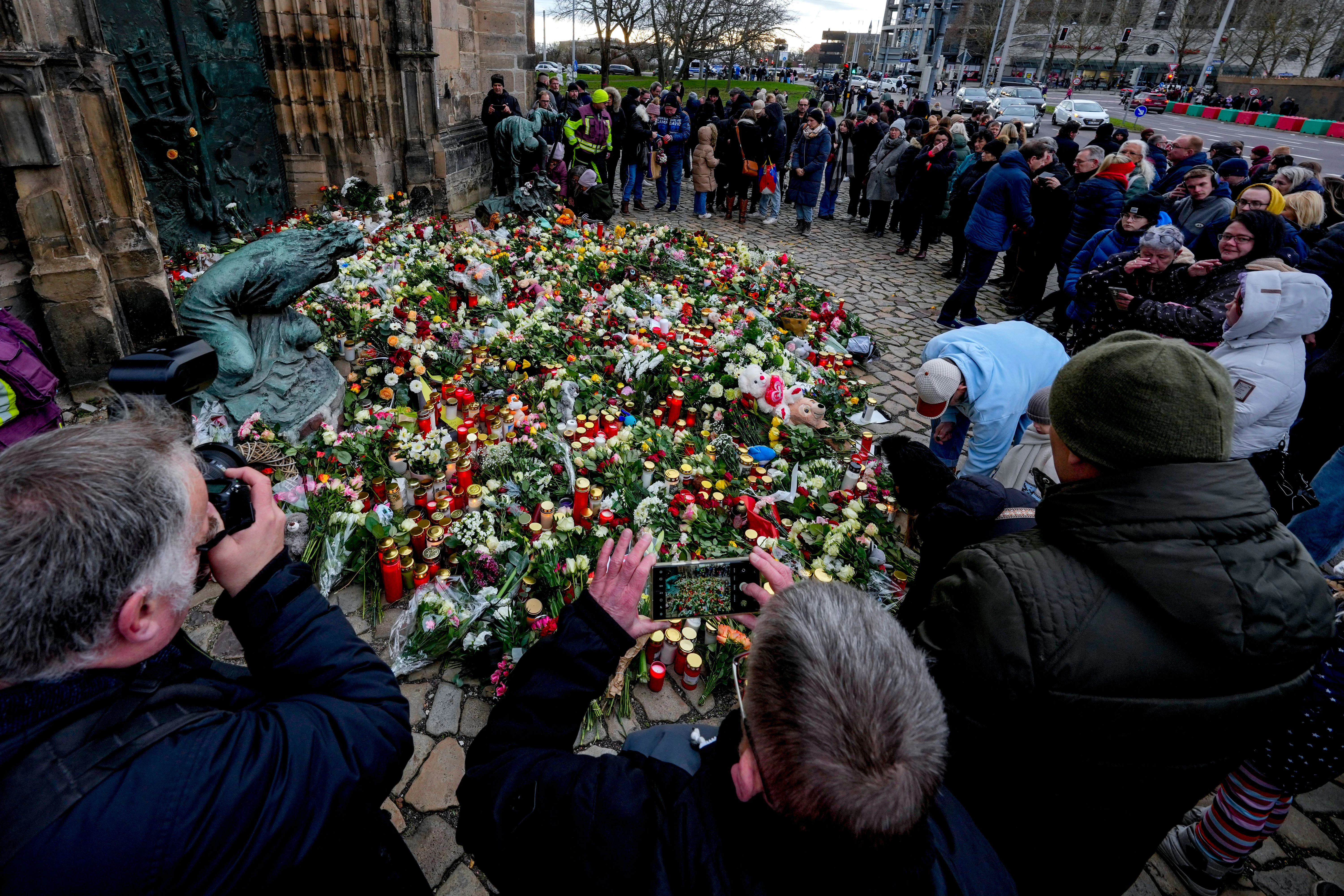 Menschen legen Blumen am Eingang einer Kirche in der Nähe des Weihnachtsmarktes nieder, wo am Freitagabend ein Auto in eine Menschenmenge fuhr.
