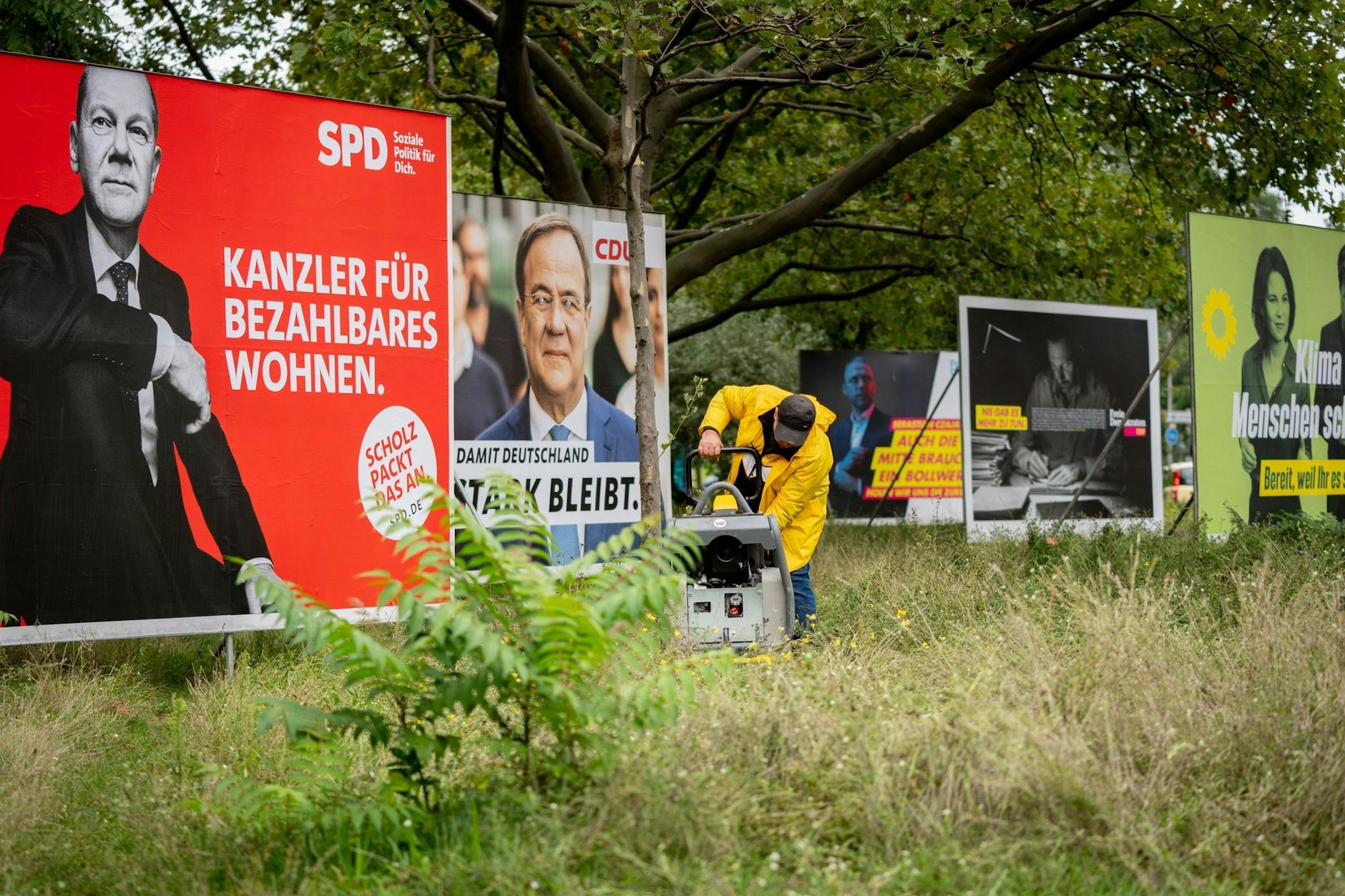 Ein Arbeiter steht am Morgen vor den großflächigen Wahlplakaten für die Bundestagswahl.