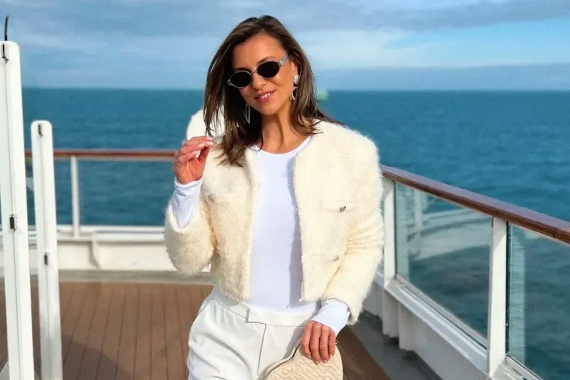 Laura Wontorra ganz in Weiß mit Felljäckchen und Sonnenbrille auf ihrer Aussteigerreise.