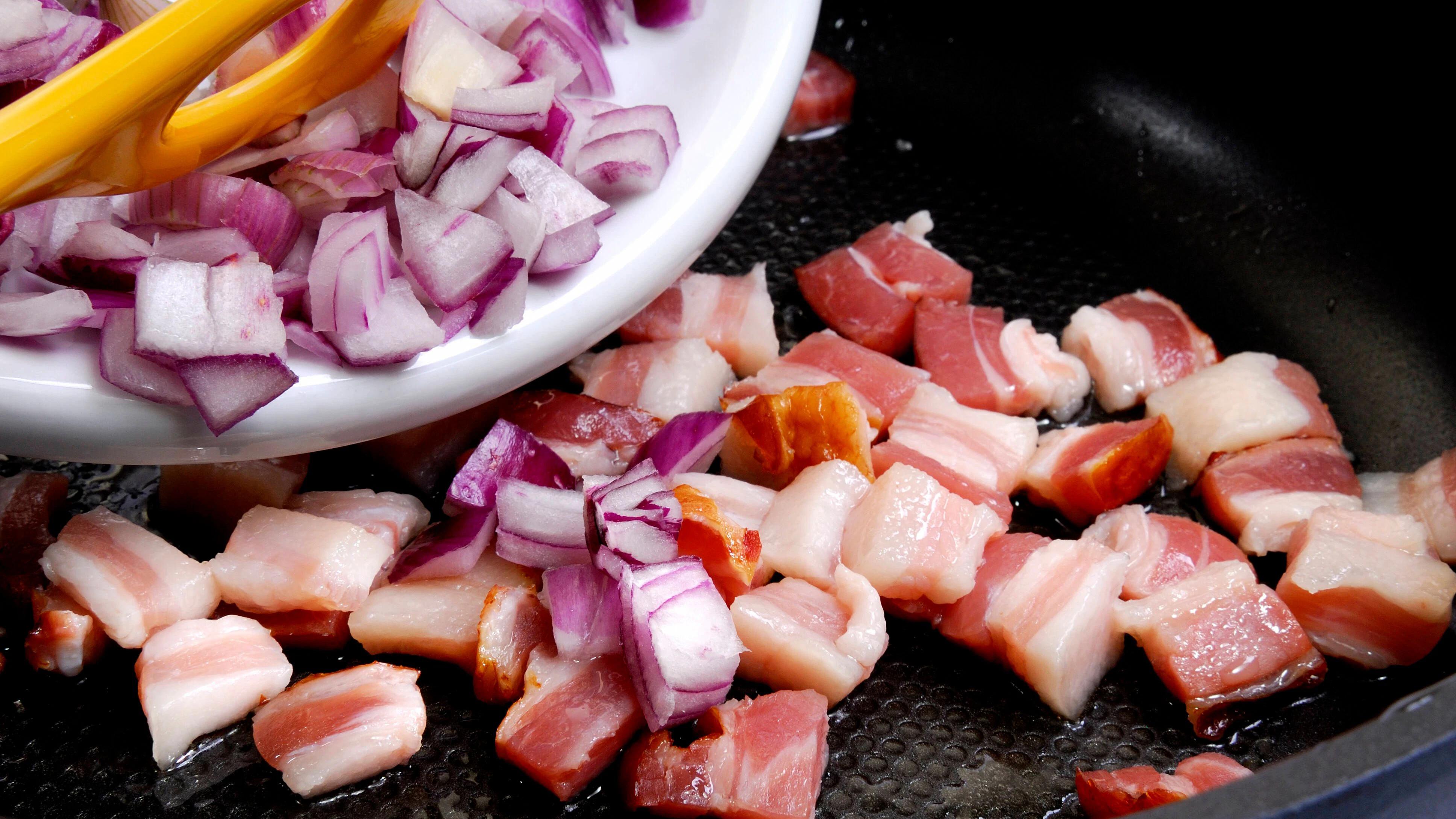 Der Speck für den Knödelauflauf wird gebraten, bis er knusprig ist.