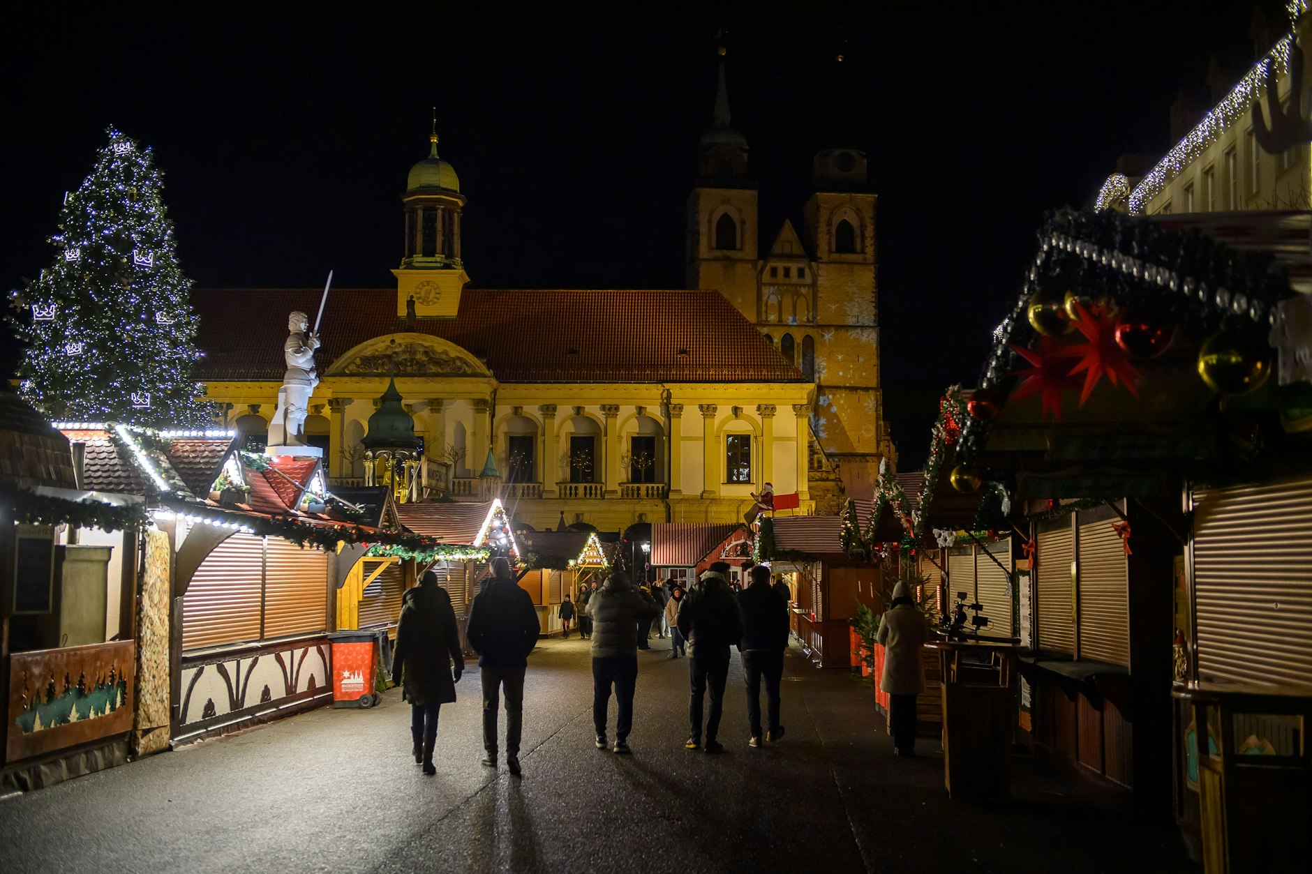 Passanten gehen nach Einbruch der Dunkelheit über den geschlossenen Magdeburger Weihnachtsmarkt. Hier fuhr Taleb A. mit seinem BMW durch die Menschenmenge.
