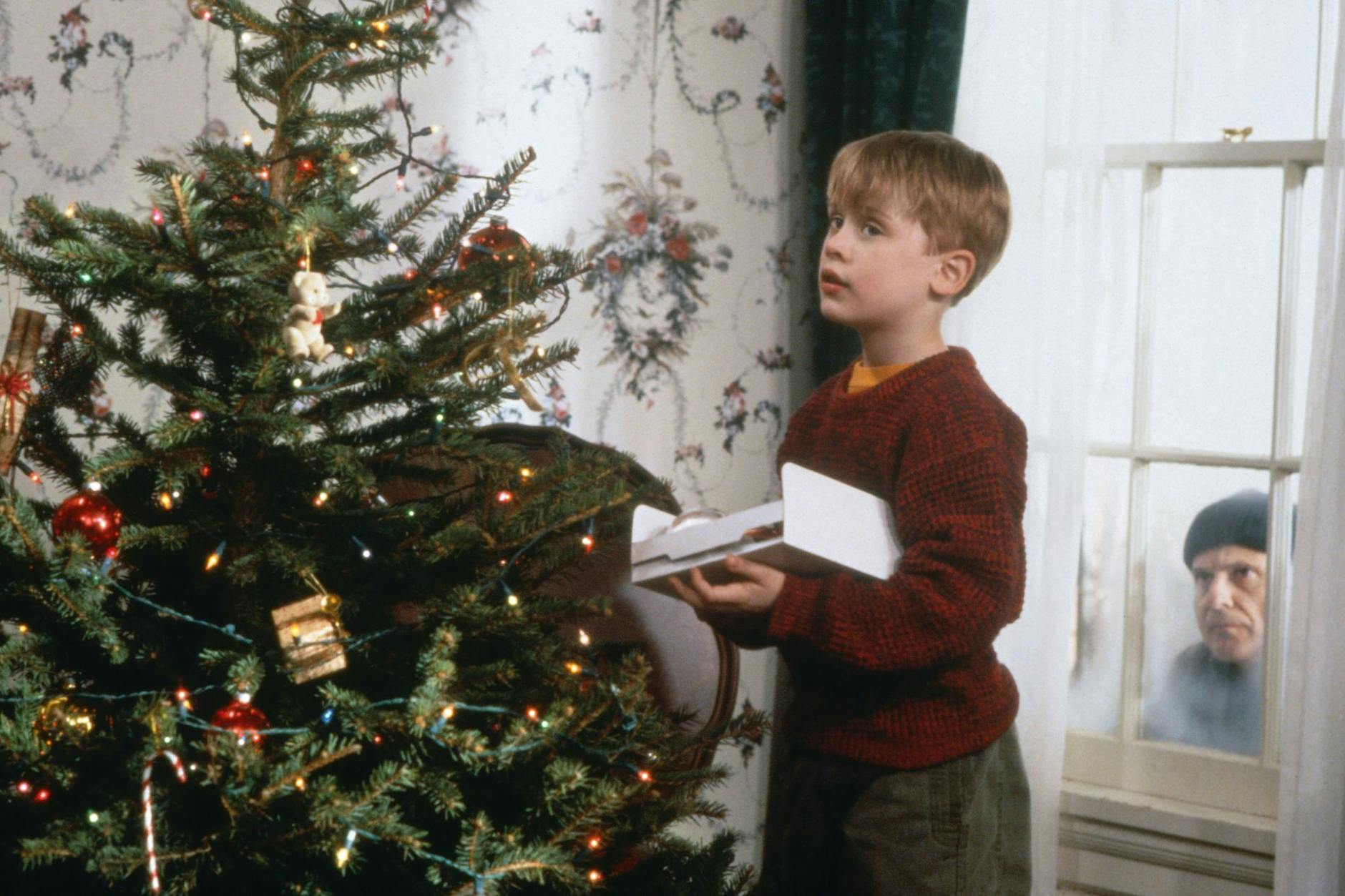 Während der nichts ahnende Kevin (Macaulay Culkin, l.) den Weihnachtsbaum schmückt, lauert Harry (Joe Pesci, r.) auf eine Gelegenheit, das Haus auszurauben: Szene aus dem Film „Kevin – Allein zu Haus“.