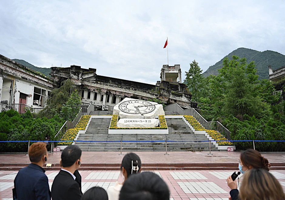 Menschen besichtigen die Ruinen der Xuankou-Mittelschule, die heute eine Gedenkstätte für das Erdbeben in Wenchuan 2008 sind.
