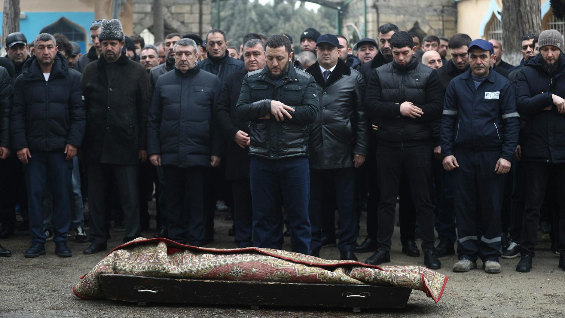 Menschen nehmen in Baku an der Beerdigung eines Dreizehnjährigen teil, der beim Absturz des ums Leben kam. Der Körper ist von einem Teppich umhüllt.