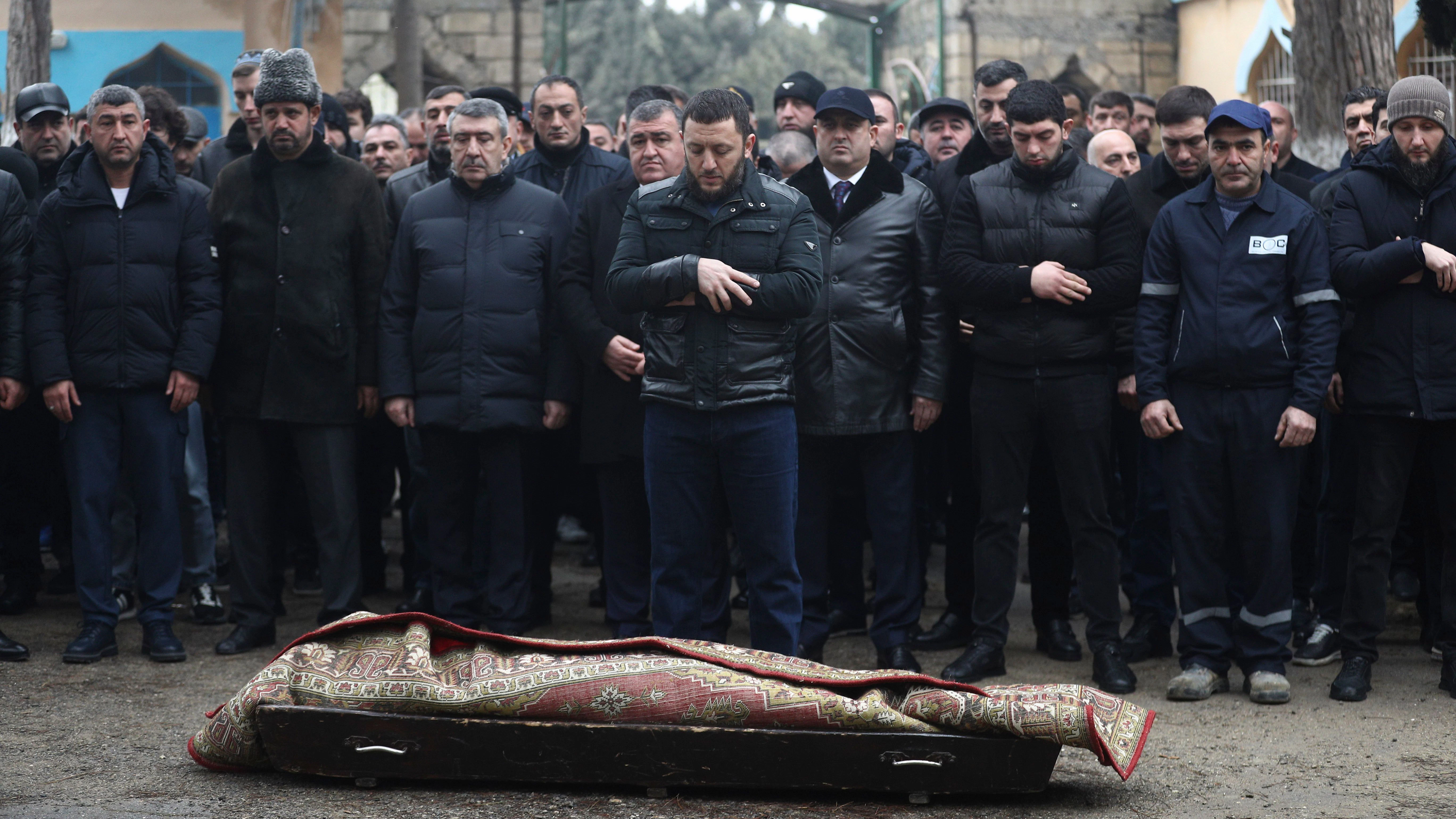 Menschen nehmen in Baku an der Beerdigung eines Dreizehnjährigen teil, der beim Absturz des ums Leben kam. Der Körper ist von einem Teppich umhüllt.