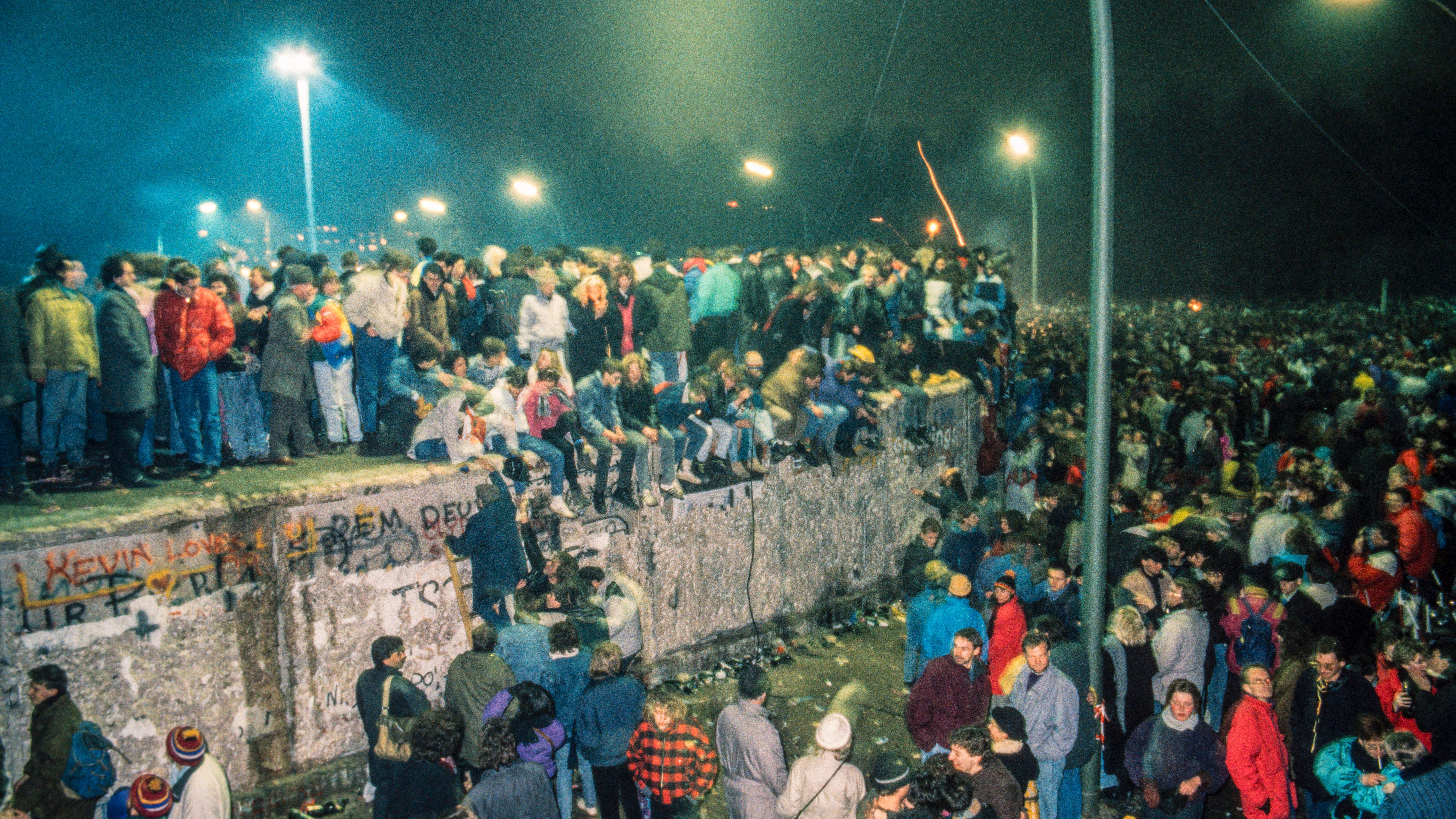 Silvester 1989: Dicht gedrängt stehen die Menschen aus Ost und West auf der Mauer seitlich vom Brandenburger Tor.