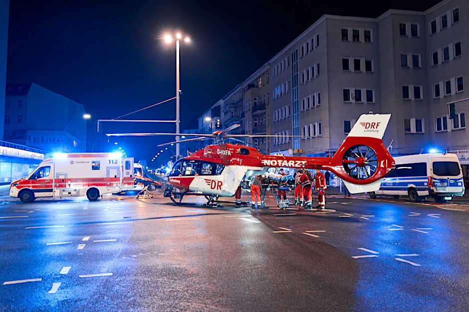 Krankenwagen, Polizei und ein Rettungshubschrauber stehen in der Nacht am Tatort in Schöneberg.