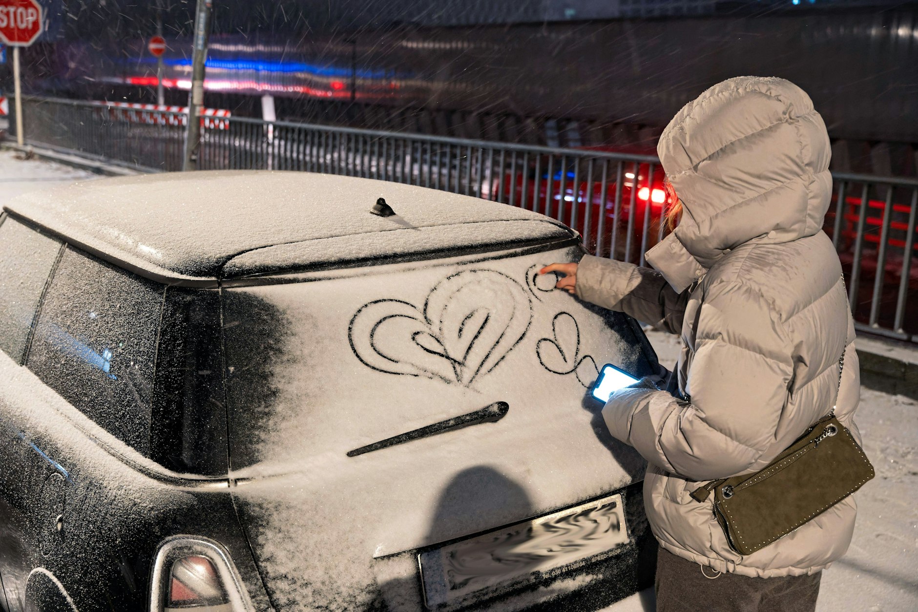 Auf ein schneebedecktes Auto wird ein Herz in die weiße Pracht gemalt.