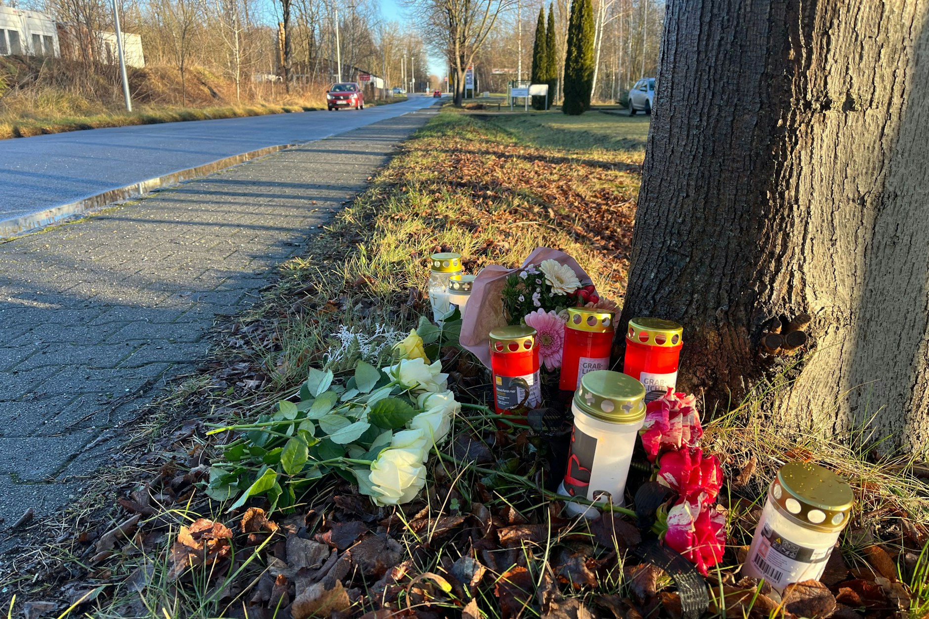 Blumen und Kerzen stehen und liegen am Tatort. Ein Polizist war am Dienstag (07.01.2024) bei der Fahndung nach Autodieben hier von einem Auto erfasst und getötet worden.