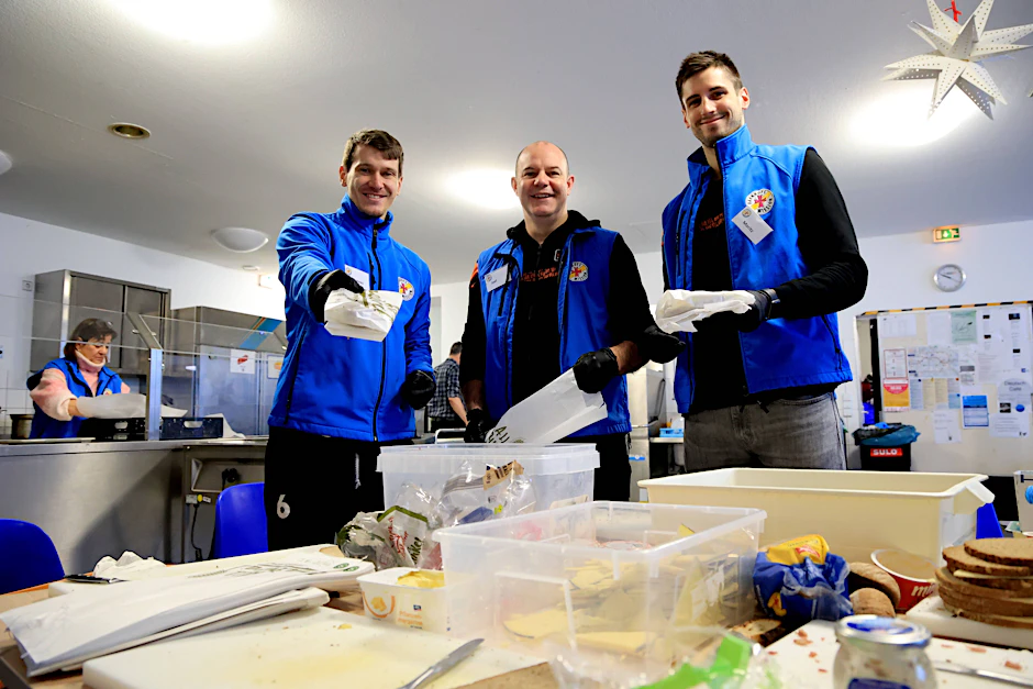 Die Stullen sind geschmiert: Johannes Tille, Trainer Joel Banks und Moritz Reichert (v.l.) von den BR Volleys helfen bei der Vorbereitung und Essensausgabe in der Berliner Bahnhofsmission am Zoo.