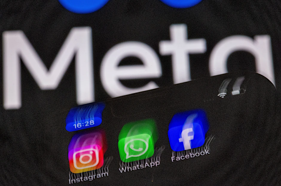 Die Apps Instagram, Facebook und WhatsApp auf dem Display eines Smartphones vor dem Logo des Internetkonzerns Meta. (Illustration)
