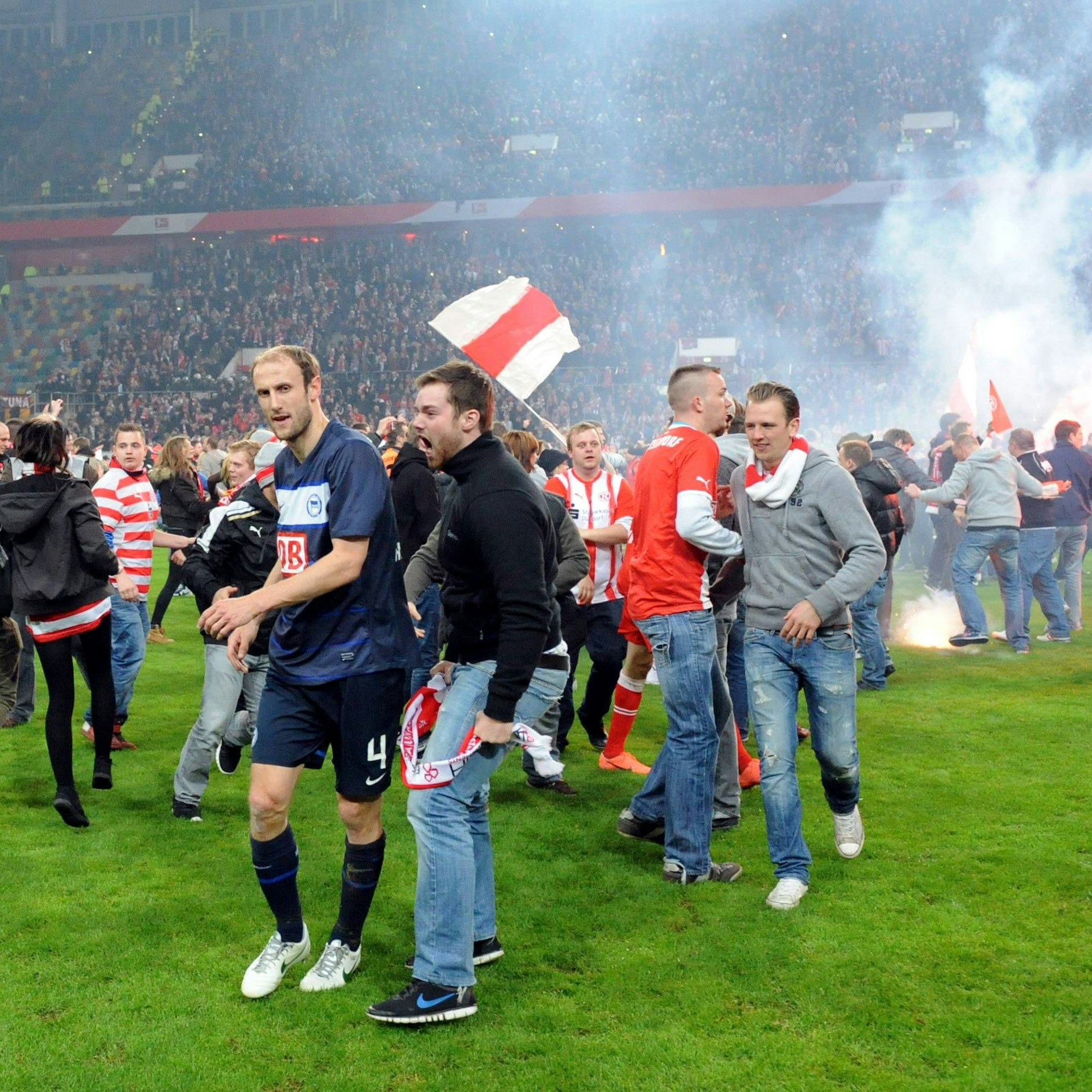 Mai 2012 in Düsseldorf: Herthas Roman Hubnik wird beim Platzsturm von einem Fortuna-Fan angepöbelt. Bengalos brennen im Hintergrund. Damals wies der DFB die Klage von Hertha BSC ab, weil angeblich das Spiel regulär beendet wurde..