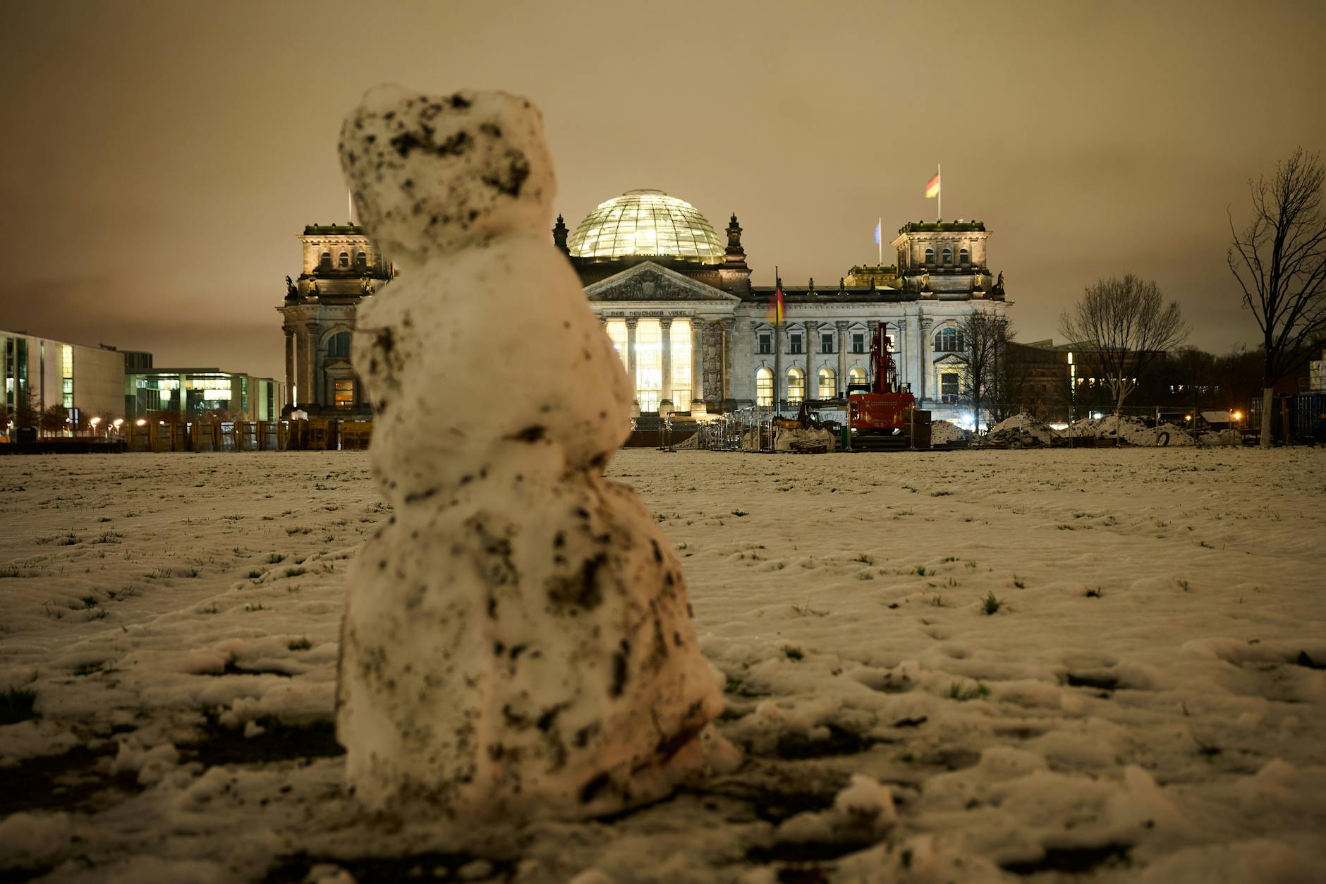Ein Schneemann steht auf der Wiese vor dem Reichstagsgebäude.