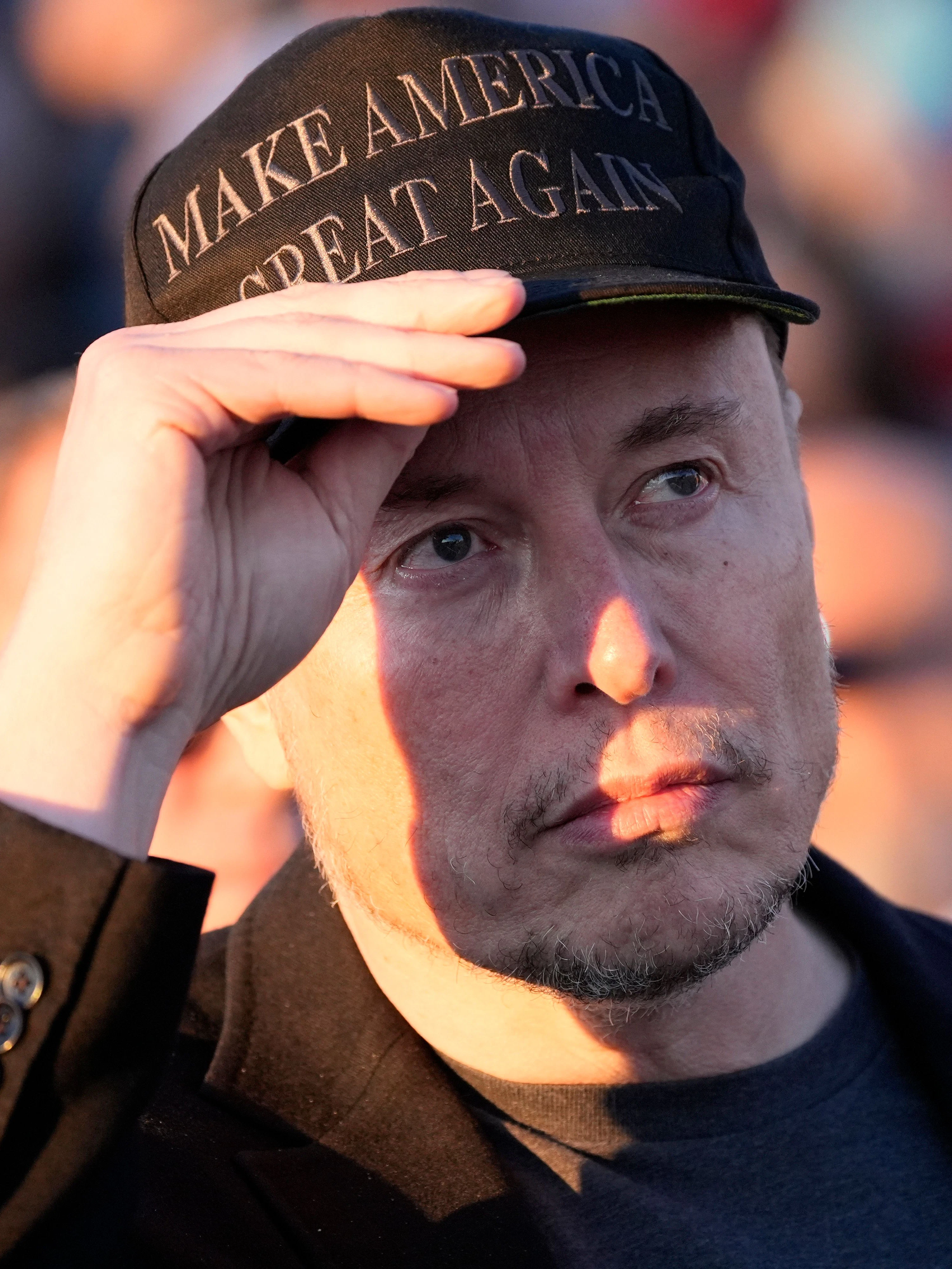 Elon Musk mit einer Kappe des Wahlspruchs von Donald Trump: Make America Great Again