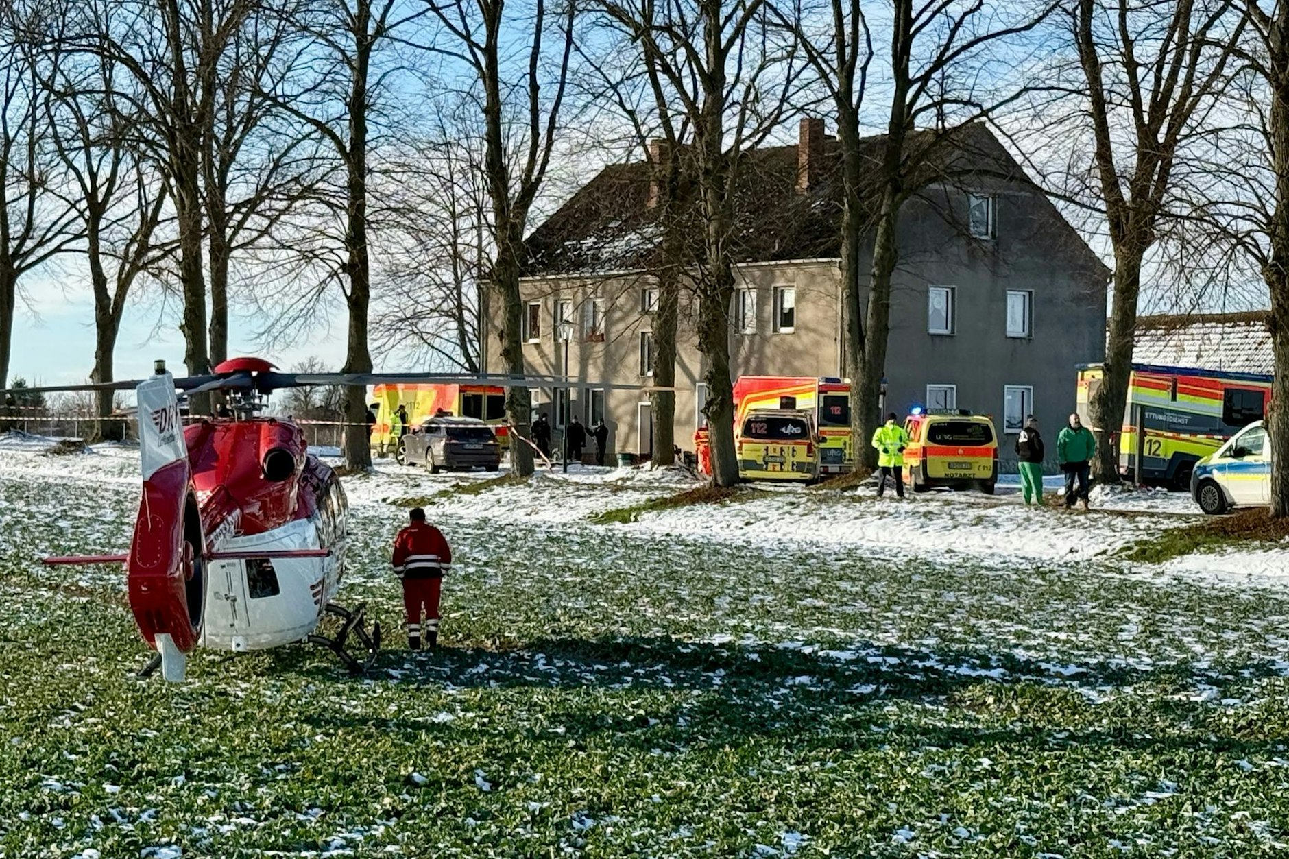 Einsatzkräfte und ein Rettungshubschrauber vor dem Haus in Casekow, in dem sich die Bluttat ereignete.