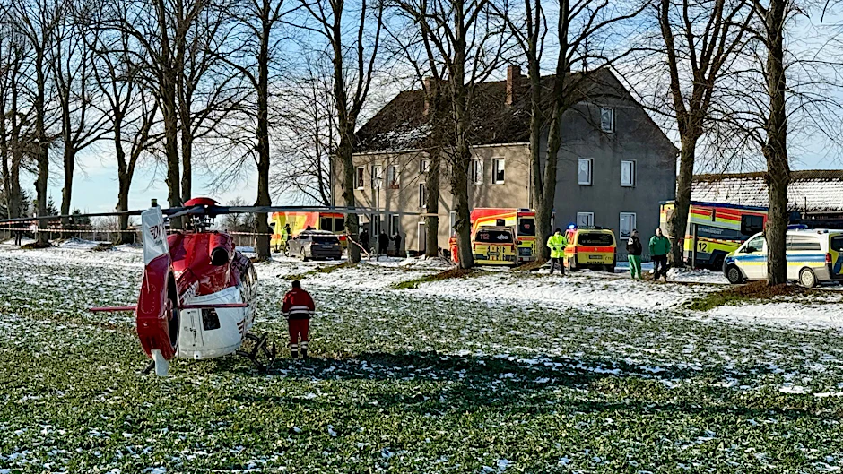 Einsatzkräfte und ein Rettungshubschrauber vor dem Haus in Casekow, in dem sich die Bluttat ereignete. 