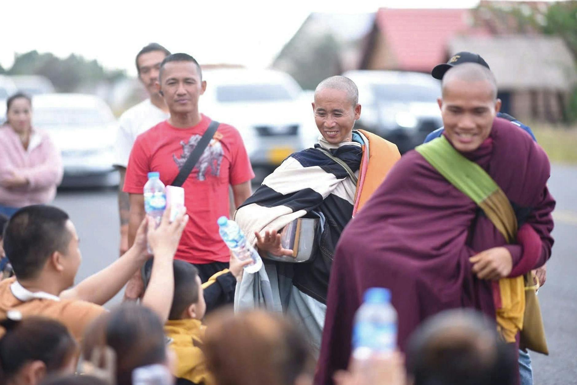 Der vietnamesische Mönch Thich Minh Tue (Mitte) mit seinen Begleitern nahe Ubon Ratchathani im Norden von Thailand. Fans versorgen mit Getränken und Essen.