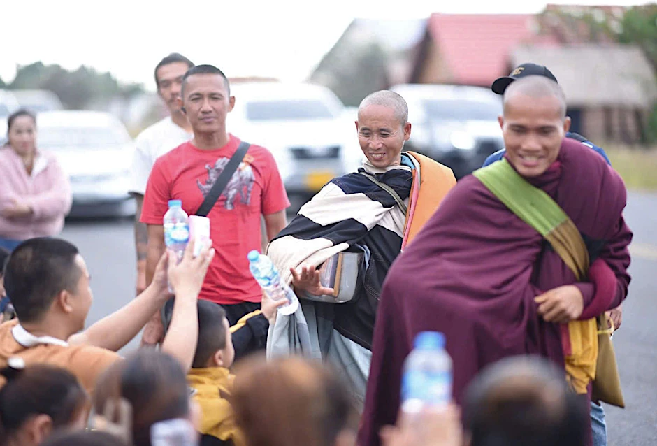 Der vietnamesische Mönch Thich Minh Tue (Mitte) mit seinen Begleitern nahe Ubon Ratchathani im Norden von Thailand. Fans versorgen mit Getränken und Essen.
