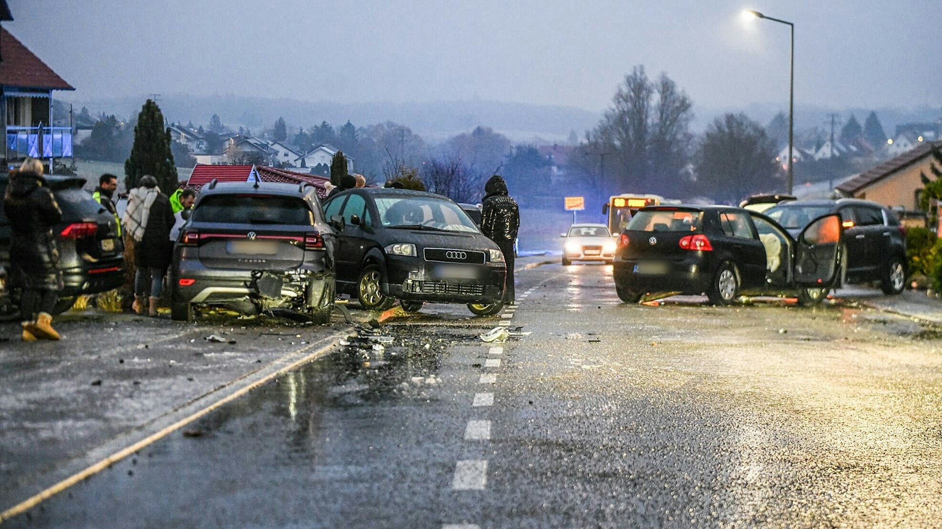 Aalen (Baden-Württemberg): Nach einem Unfall bei Glatteis mit mehreren Fahrzeugen stehen Helfer und Beteiligte an den Autos auf einer Straße. 