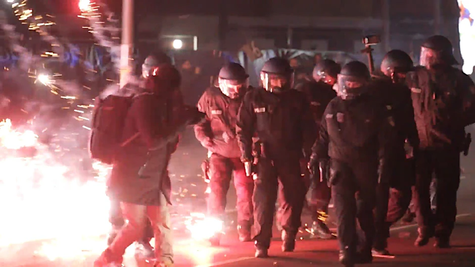 Polizisten stehen in der Silvesternacht zwischen brennendem Feuerwerk in Neukölln.