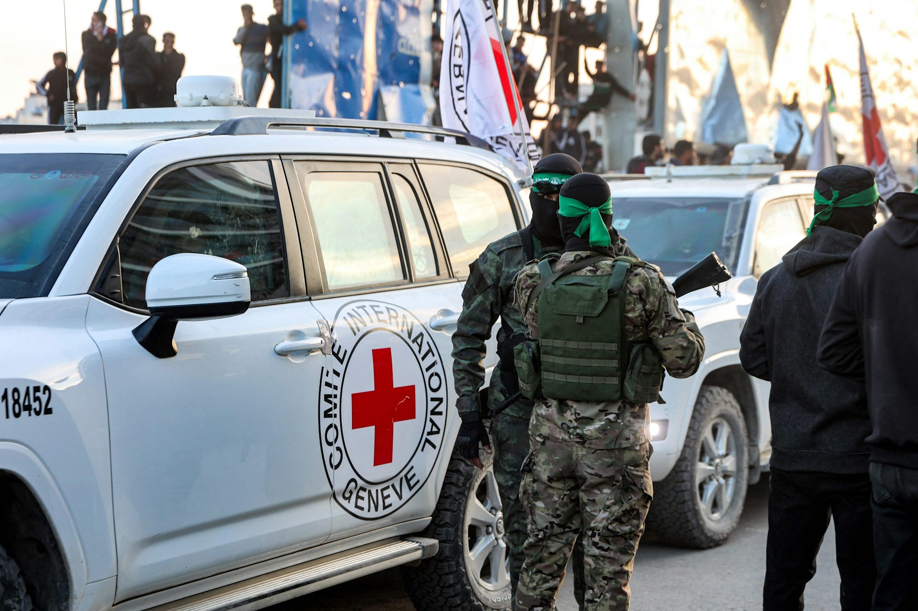 Hamas-Terroristen umringen Fahrzeuge des Internationalen Roten Kreuz.