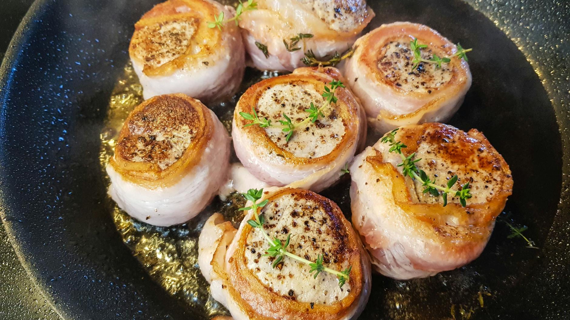 Das mit Bacon umwickelten Schweinefilet kann man am Stück oder in Medaillons geschnitten zubereiten. Erst in der Pfanne anbraten, dann im Ofen fertig garen.
