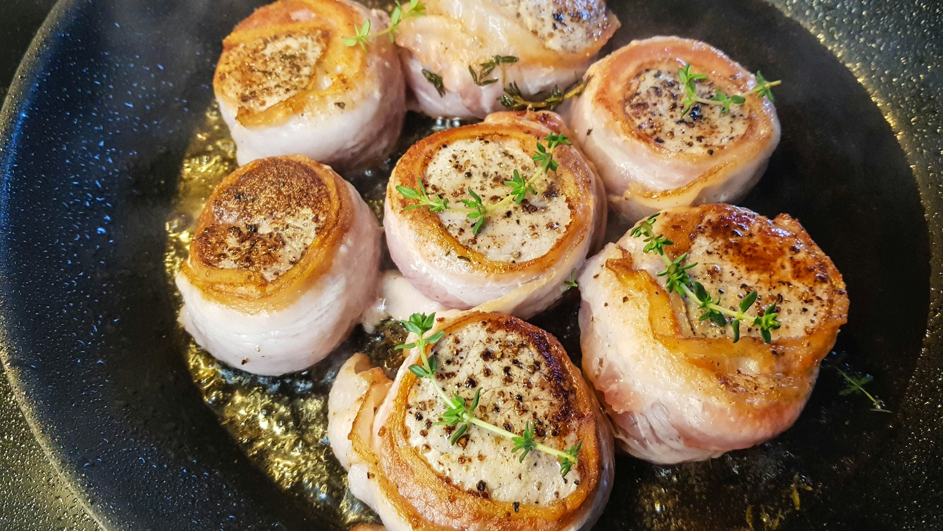Das mit Bacon umwickelten Schweinefilet kann man am Stück oder in Medaillons geschnitten zubereiten. Erst in der Pfanne anbraten, dann im Ofen fertig garen.
