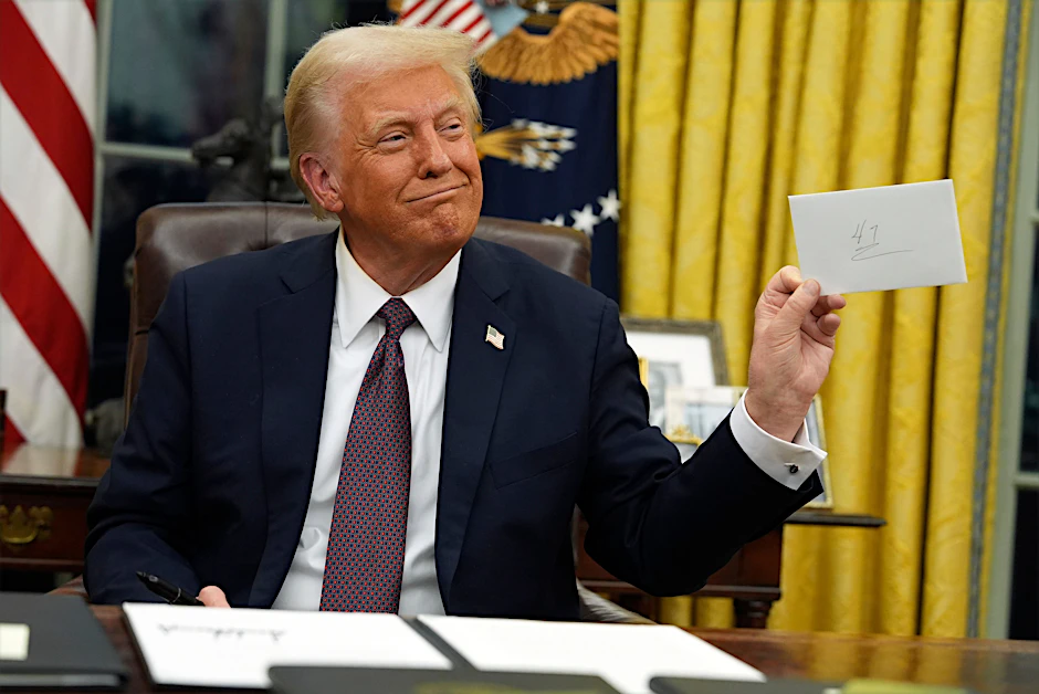 Amerikas neuer Präsident Donald Trump hält den Brief hoch, den sein Vorgänger Biden für ihn im Schreibtisch hinterlassen hat.
