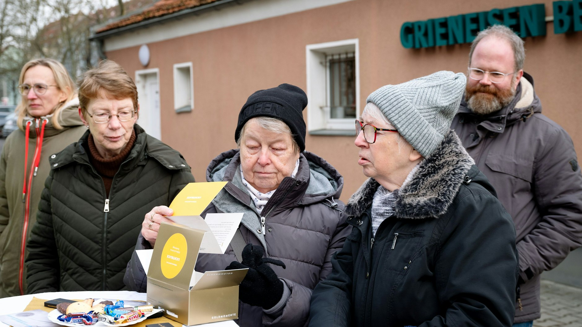Neugierig schauen Friedhofsbesucherinnen nach dem Inhalt der Boxen.