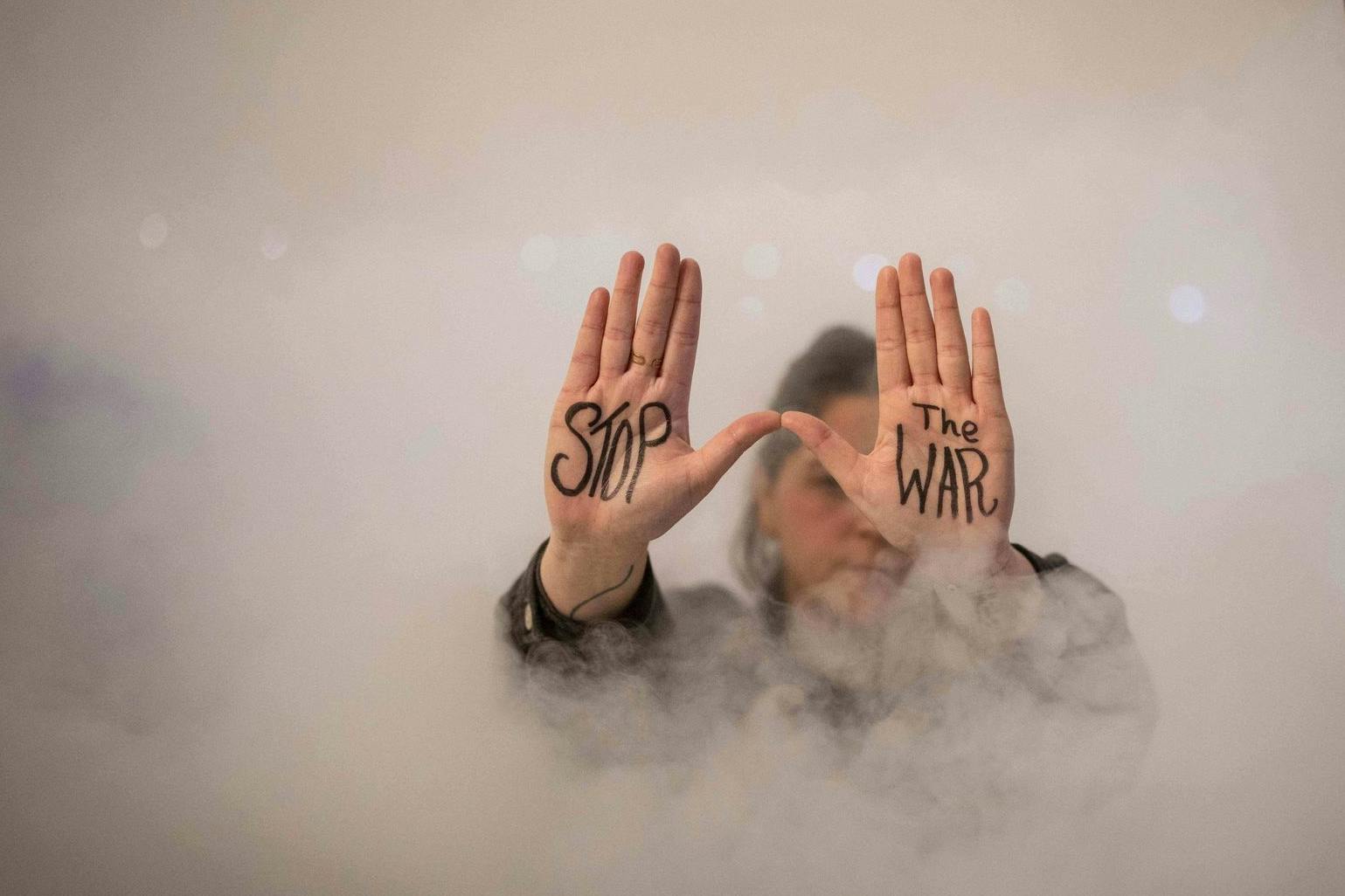 Eine Demonstrantin zeigt während eines Protests den auf ihre Handflächen geschriebenen Schriftzug „Stoppt den Krieg“.