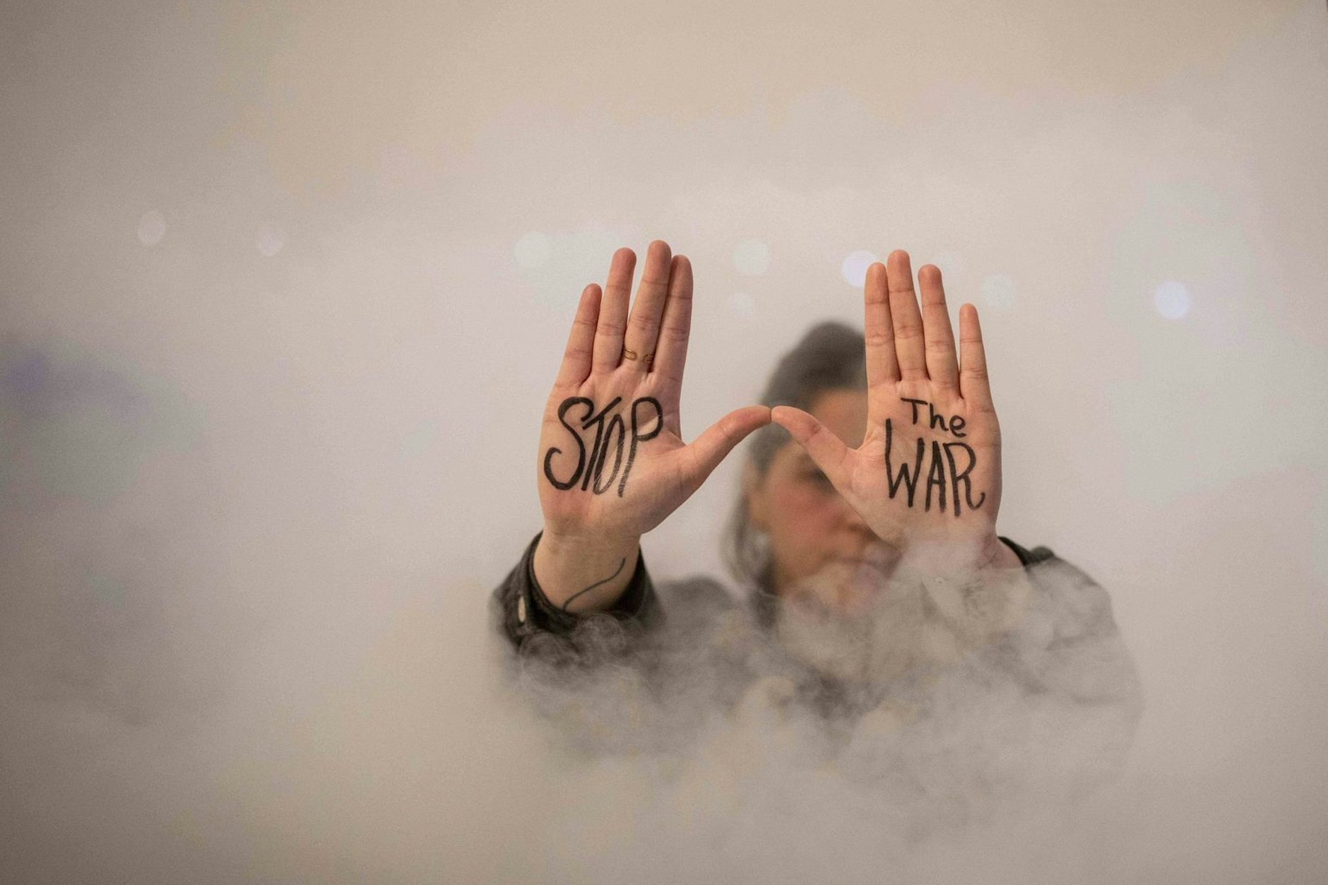 Eine Demonstrantin zeigt während eines Protests den auf ihre Handflächen geschriebenen Schriftzug „Stoppt den Krieg“.