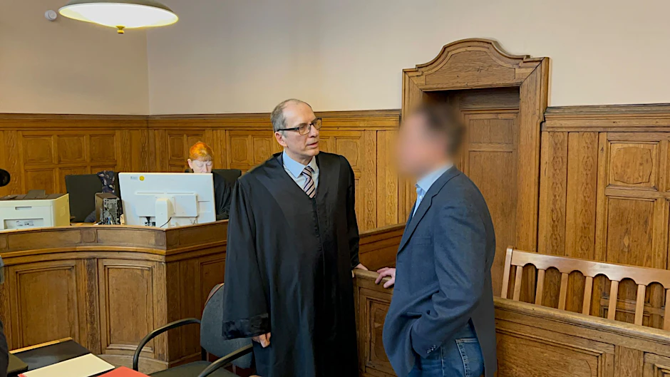 Der angeklagte Lehrer (r.) steht mit seinem Anwalt Uwe Freyschmidt im Gerichtssaal. Der 62-Jährige ist wegen Körperverletzung im Amt angeklagt.