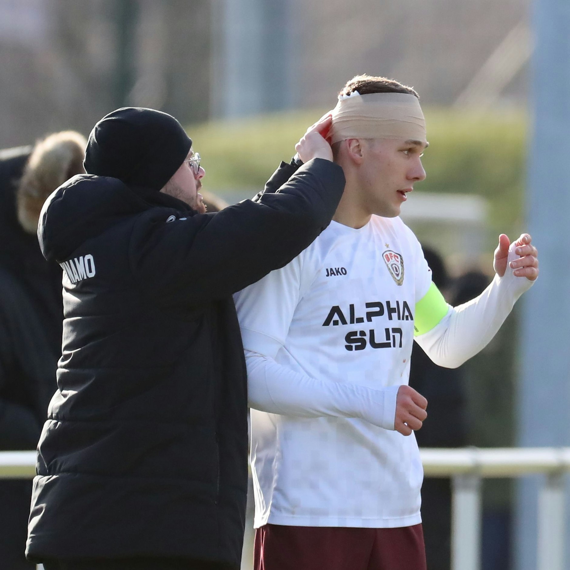 Chris Reher bekommt von BFC-Physio Pascal Kämper einen Turban-Verband angelegt und kann weiterspielen.