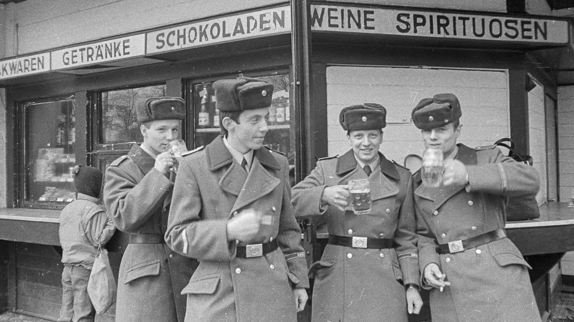Vier Soldaten der Grenztruppen der DDR stehen während ihres Ausganges Bier trinkend an einem Kiosk in Berlin-Rahnsdorf (1987). In dem Ort befand sich auch ihre Kaserne.