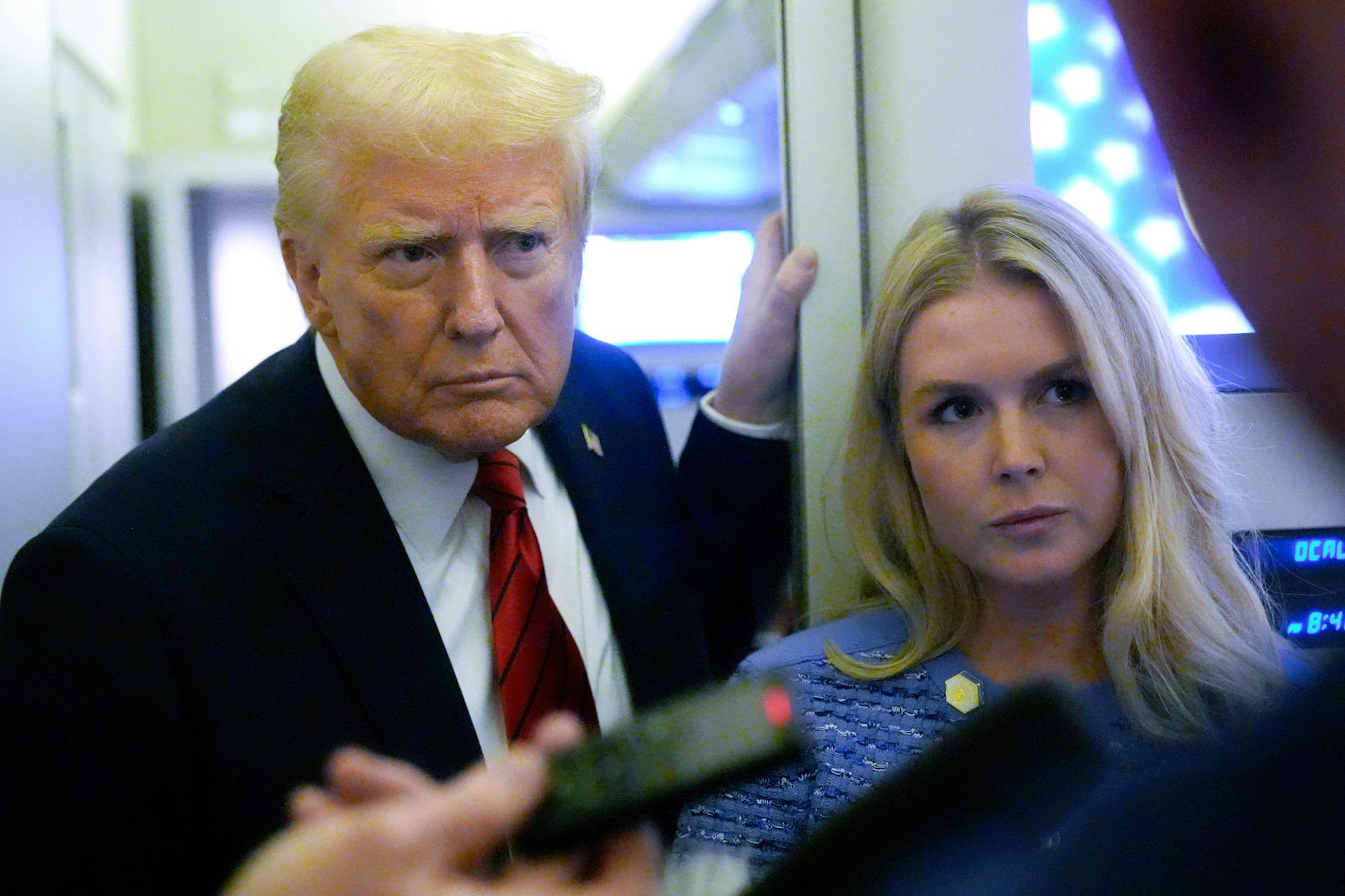US-Präsident Donald Trump spricht an Bord der „Air Force One“ mit Reportern, neben ihm die Pressesprecherin des Weißen Hauses, Karoline Leavitt.