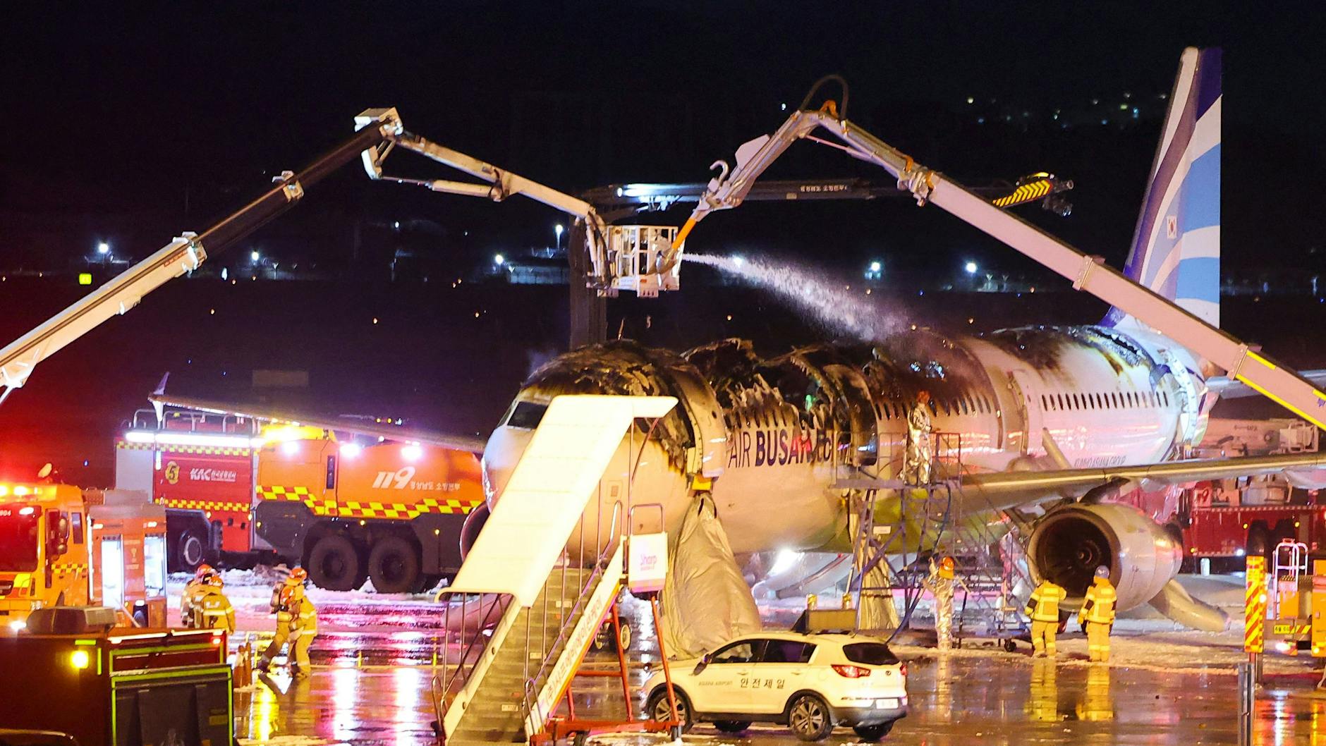 Feuerwehrleute bei dem ausgebrannten Flugzeug-Wrack.