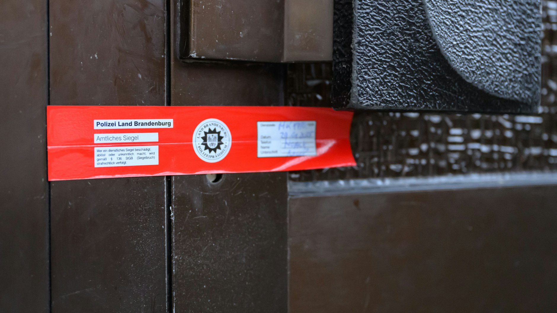 Ein Siegel der Brandenburger Polizei ist an einer Eingangstür zu einem Mehrfamilienhaus angebracht. Bei einem Brand in einer Wohnung in Frankfurt/ Oder sind drei Menschen gestorben. 