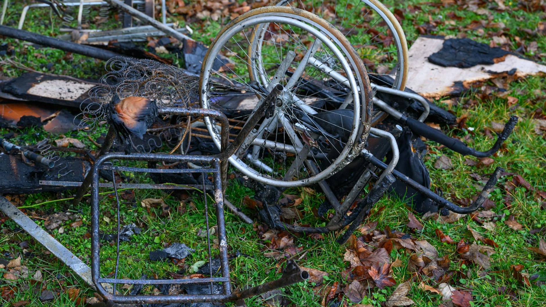 Ein verbrannter Rollstuhl sowie weitere verbrannte Gegenstände liegen auf einer Wiese vor dem Haus in Frankfurt/ Oder, in dem in der Nacht drei Menschen bei einem Feuer ums Leben kamen. 