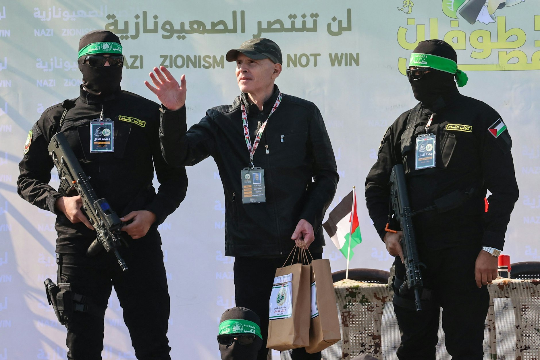 Hamas-Kämpfer mit der US-israelischen Geisel Keith Siegel auf einer Bühne vor seiner Übergabe an das Rote Kreuz