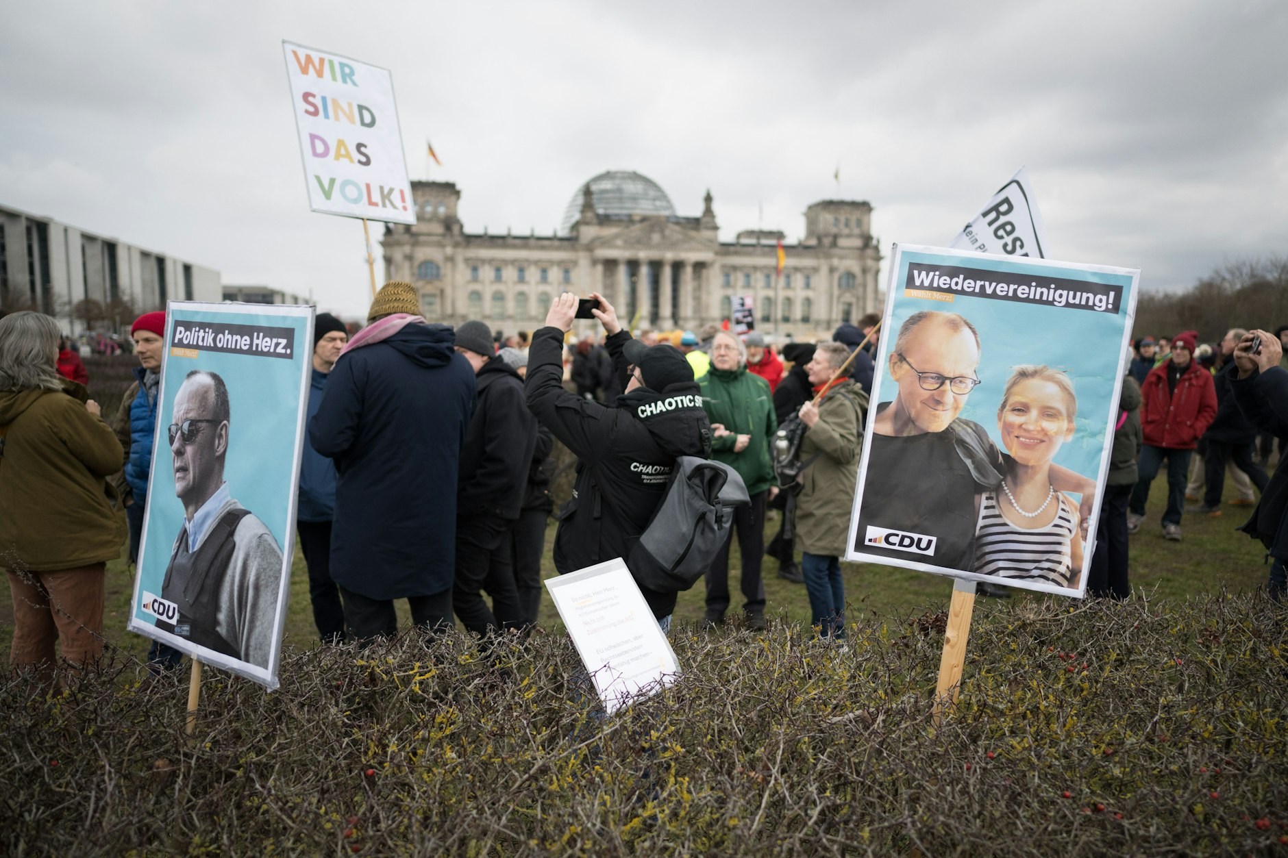 Schilder stecken während der Demonstration unter dem Motto „Aufstand der Anständigen – Demo für die Brandmauer“ in einer Hecke vor dem Reichstag.