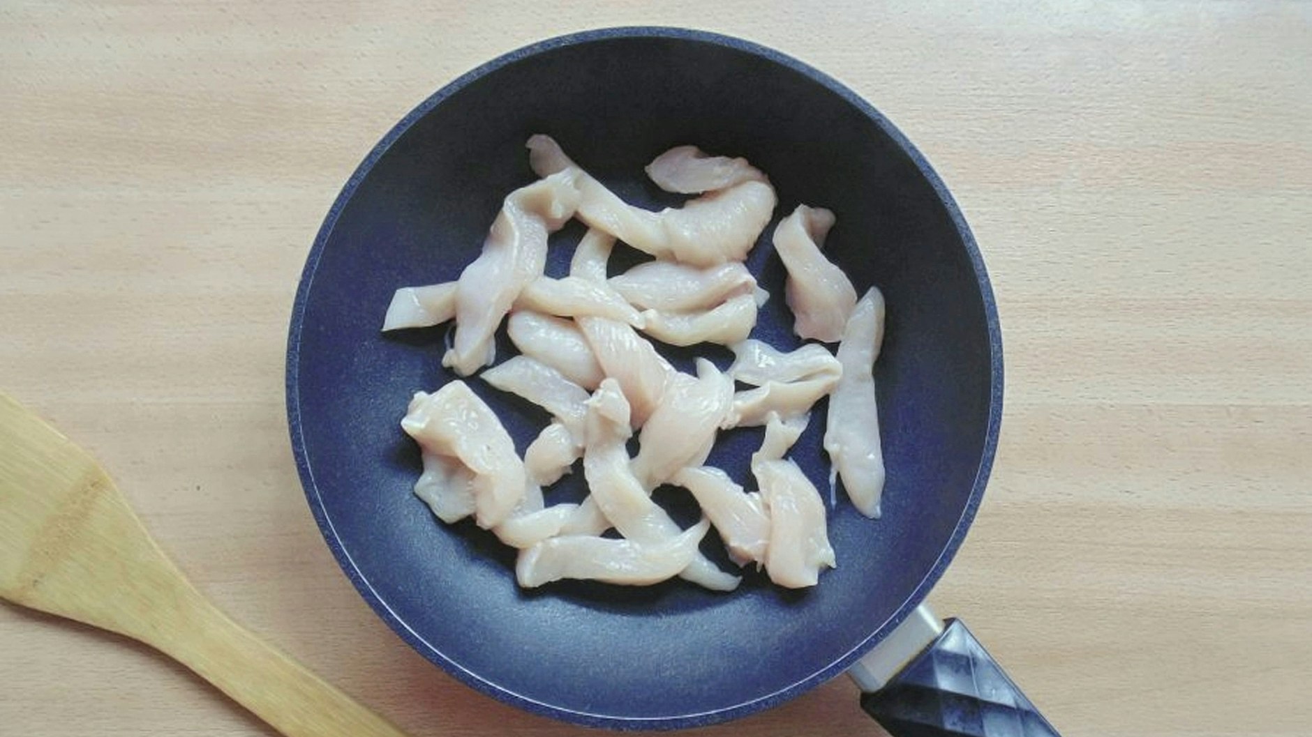Das Hähnchenfilet für das Chicken-Curry wird in Streifen geschnitten und zusammen mit den Schalotten als Erstes angebraten