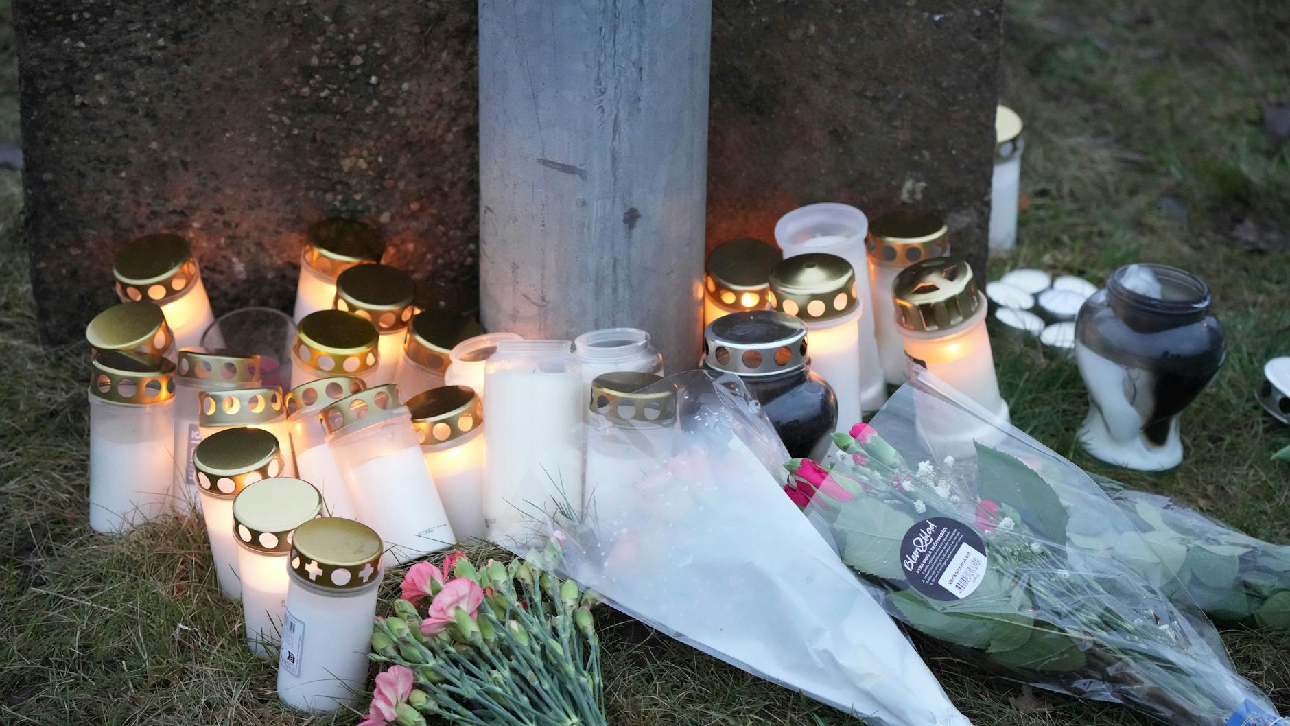 Menschen haben Kerzen und Blumen an einer behelfsmäßigen Gedenkstätte in der Nähe des Campus Risbergska am Rande von Örebro abgelegt.