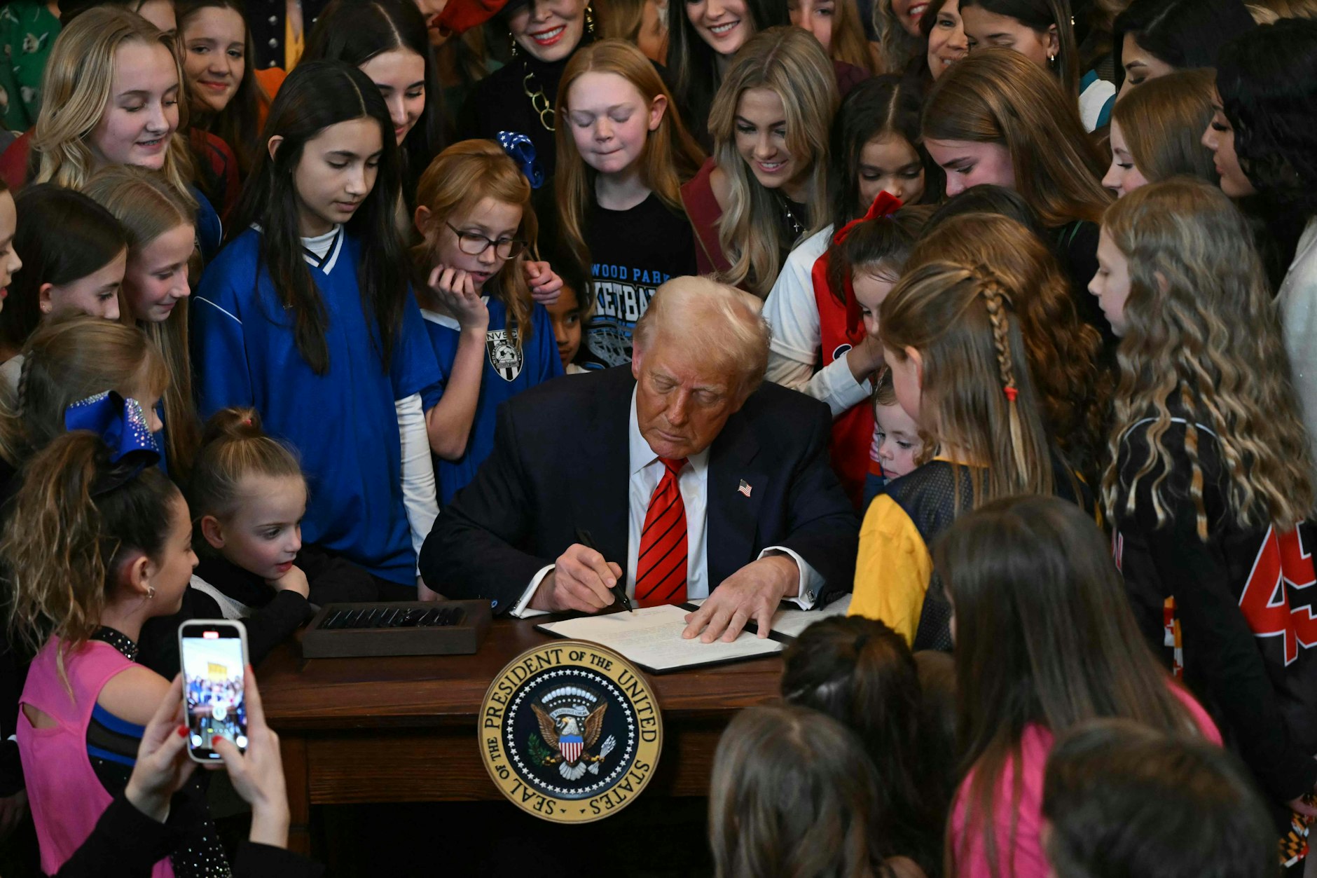 Umringt von Mädchen und Frauen: US-Präsident Donald Trump unterzeichnet das Dekret „Männer vom Frauensport fernhalten“.
