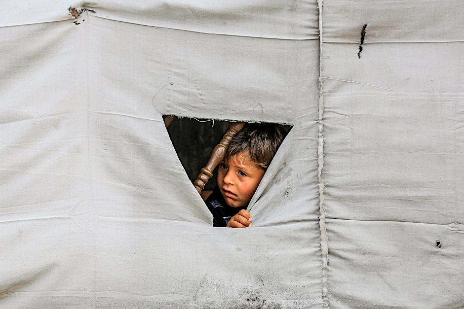 Ein Kind späht durch ein Zelt im Gazastreifen