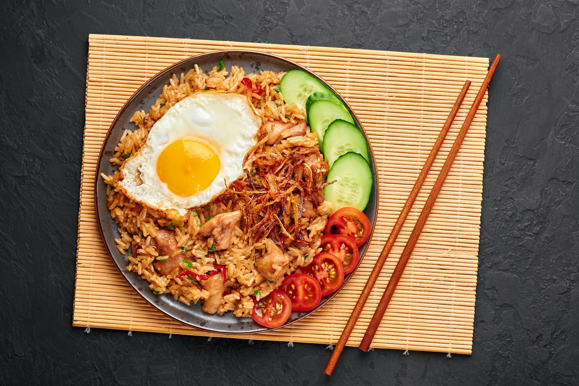 In Indonesien isst man Nasi Goreng meist mit Gabel und Reislöffel, es geht aber auch mit Stäbchen.