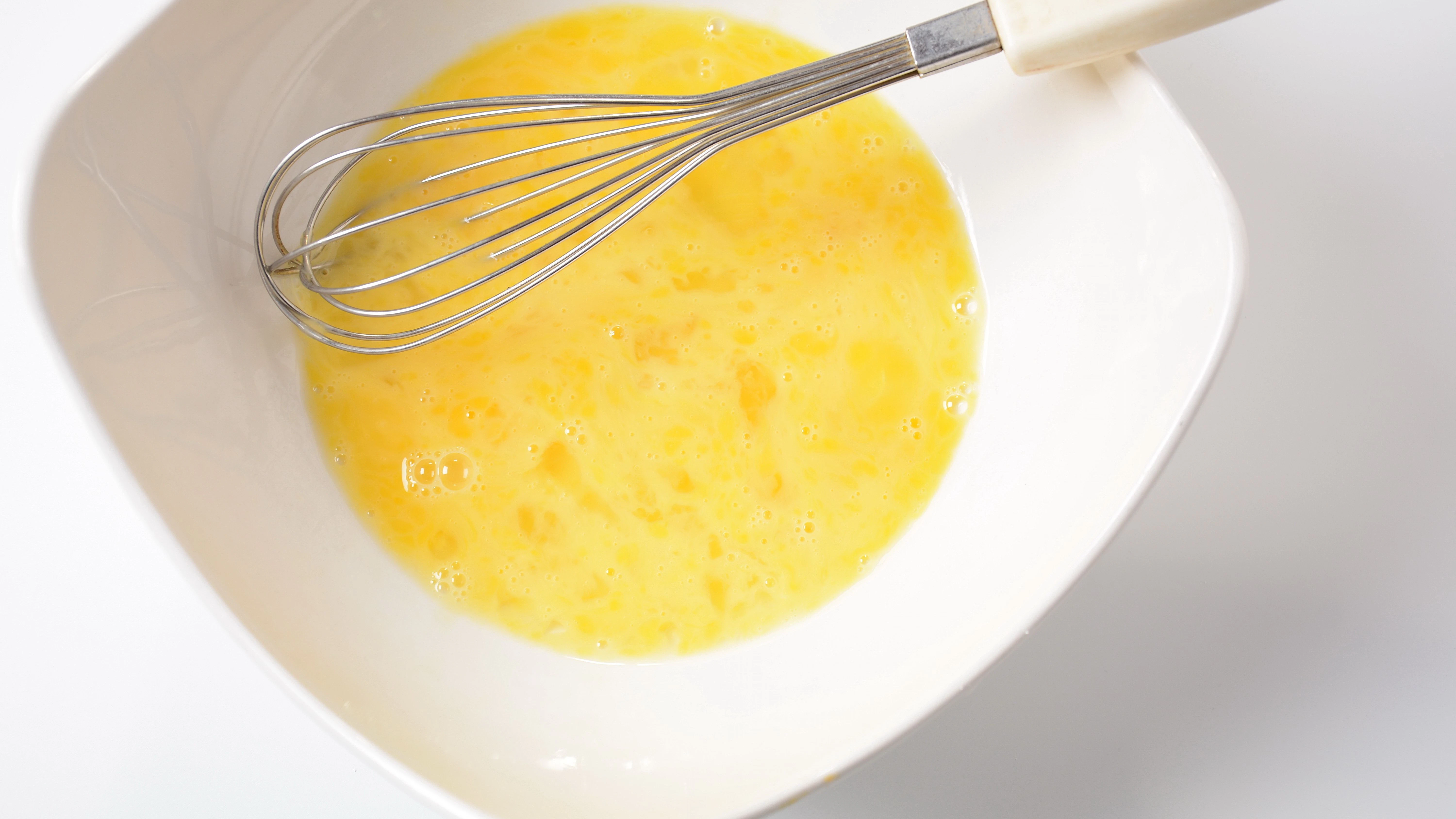 Eier und Milch werden in einer Schüssel verquirlt.