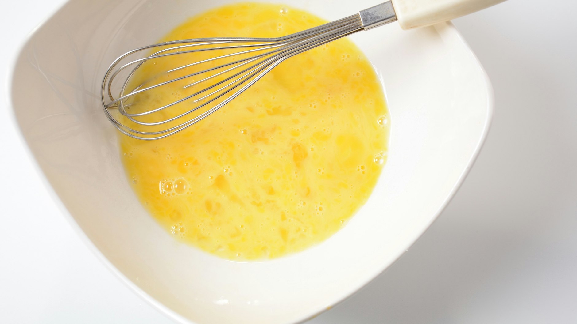 Eier und Milch werden in einer Schüssel verquirlt.